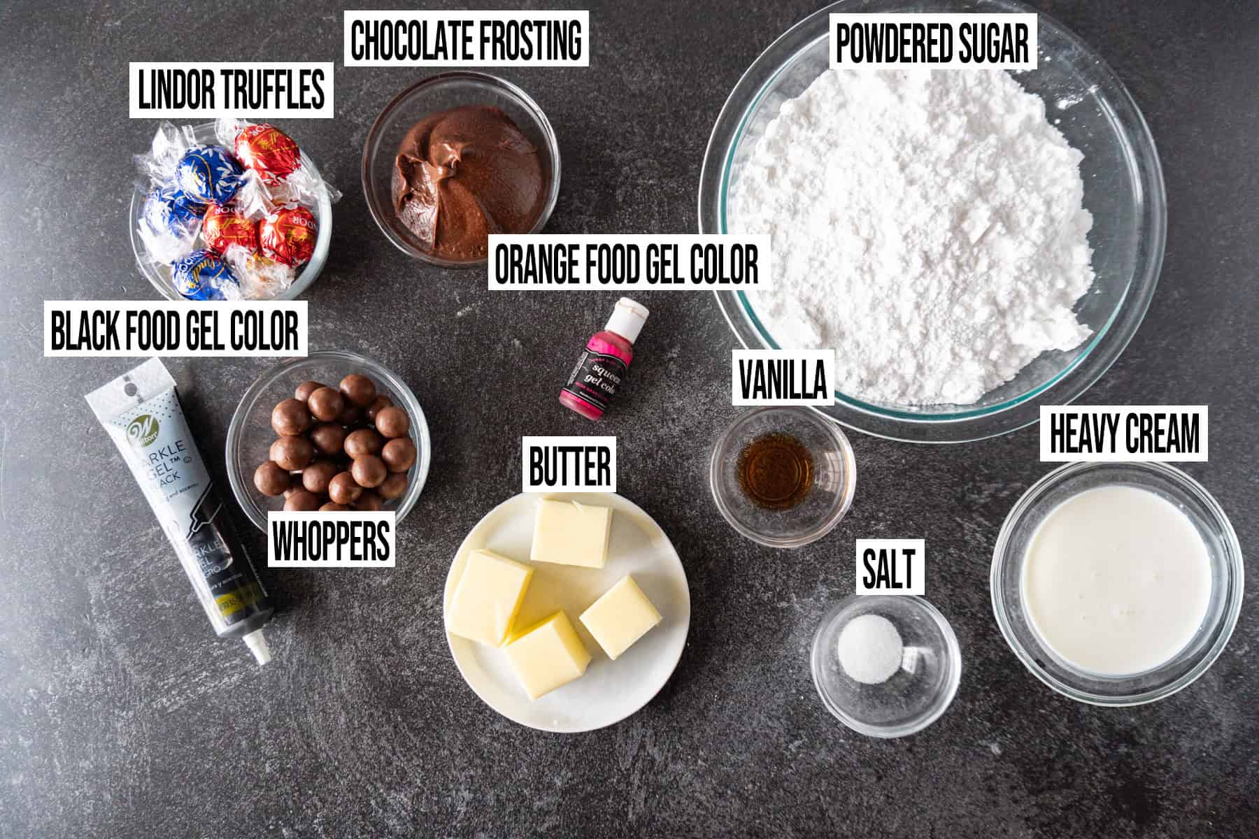 Halloween Spider Cookies frosting and decoration ingredients in individual bowls and labeled.