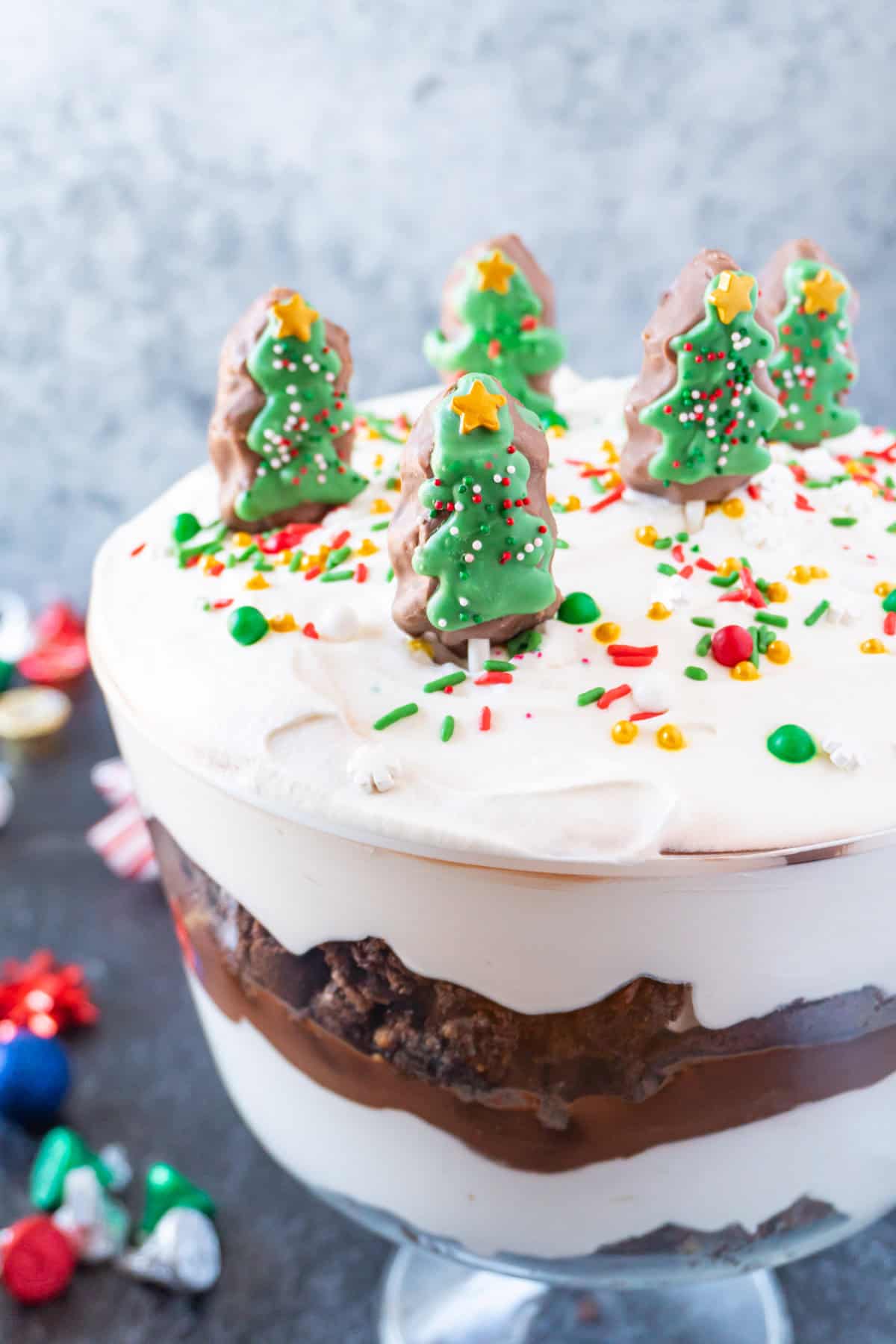 Christmas Trifle showing beautiful brownie, pudding, and whipped cream layers, topped with Christmas candies and sprinkles.