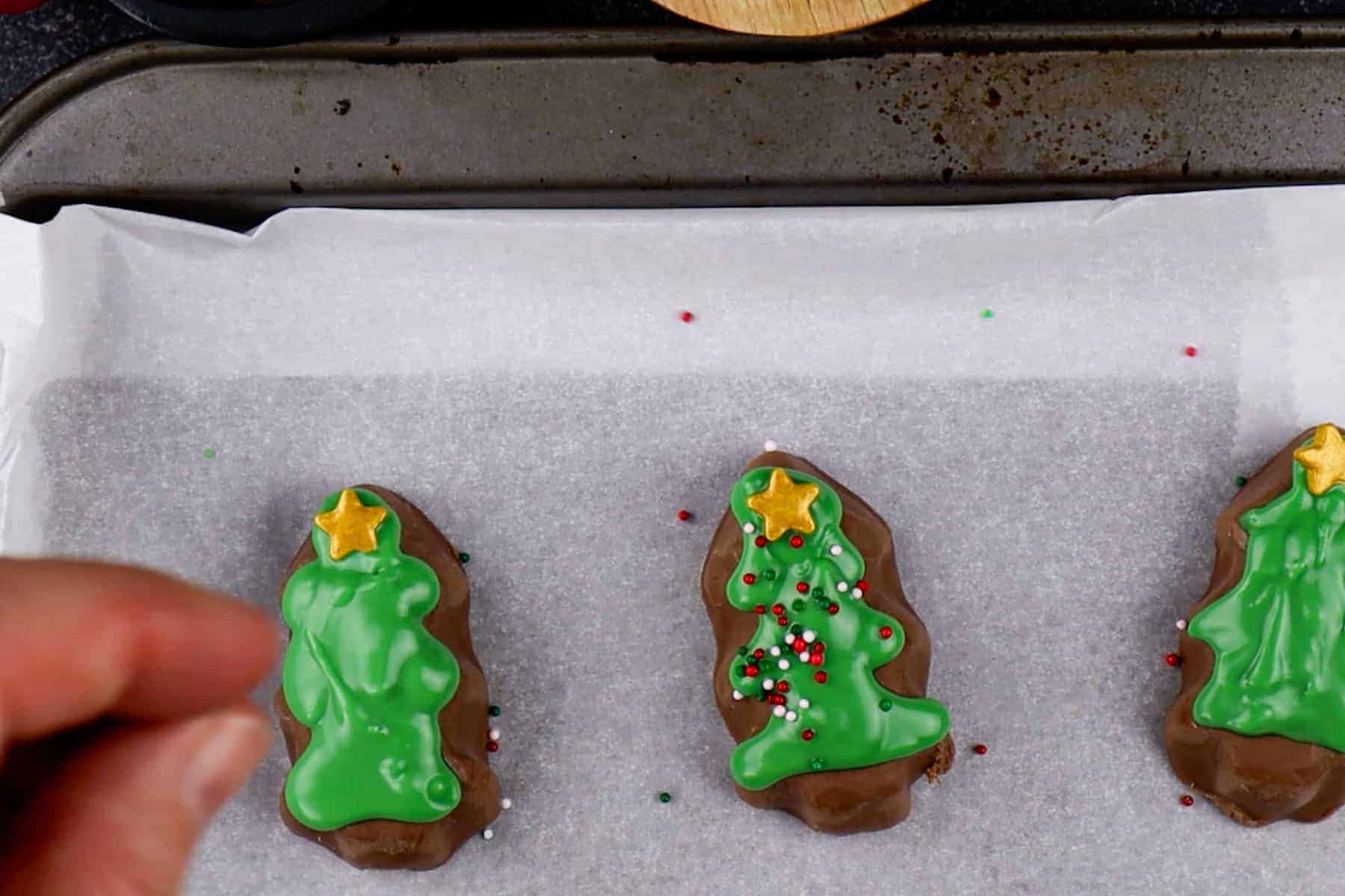adding sprinkles to decorated REESE's peanut butter trees.