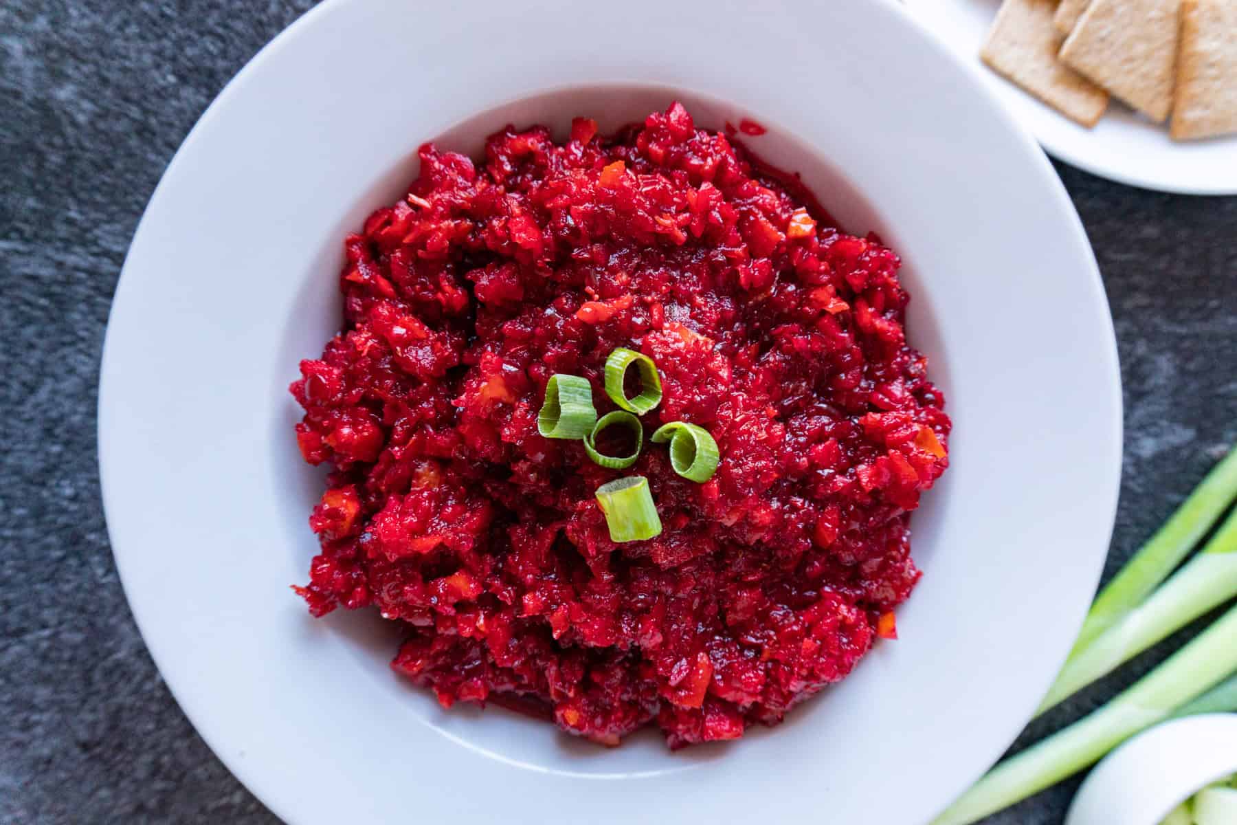cranberry relish in a white bowl garnished with green onions.