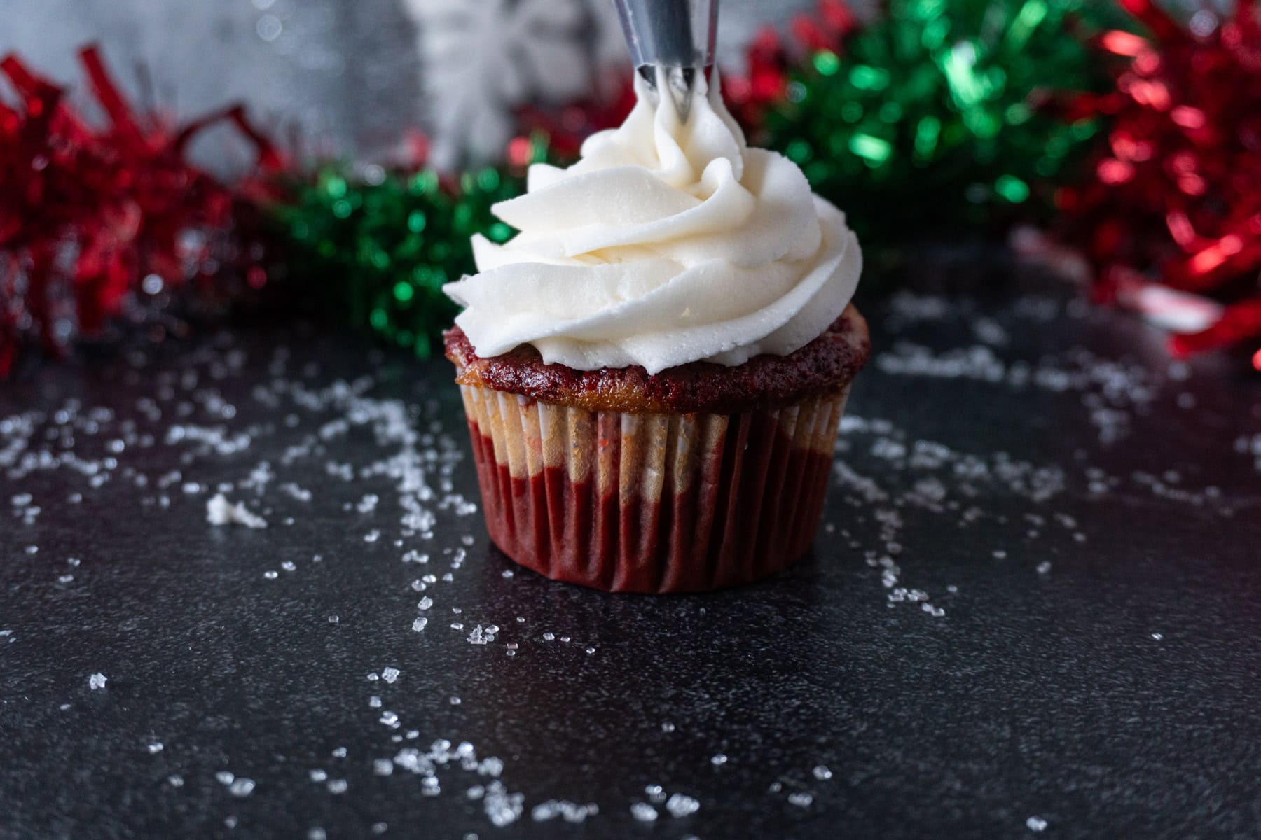 Piping on the frosting to the candy cane cupcake.
