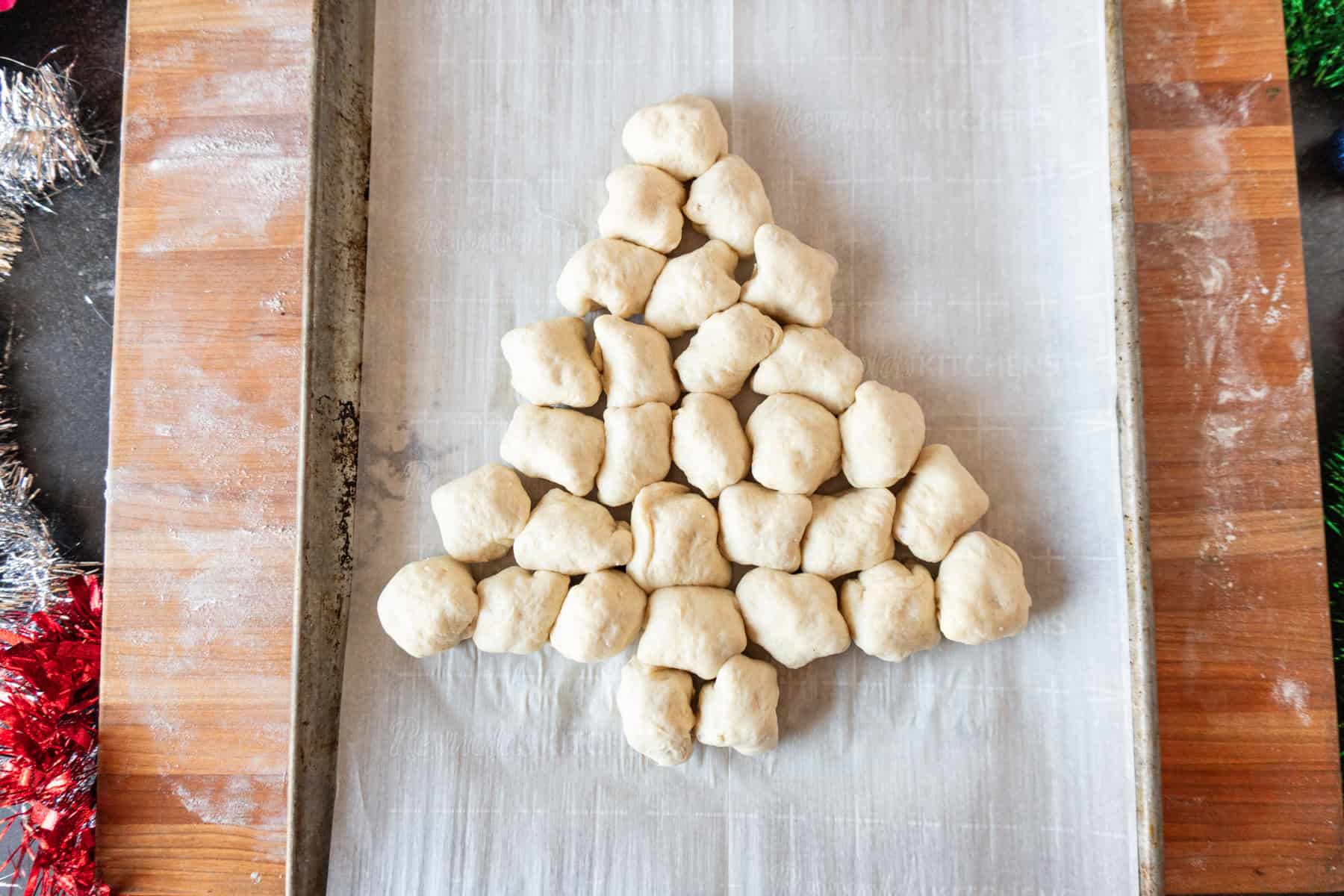 christmas appetizer dough balls rolled and in shape of a tree, before baking, on baking sheet.