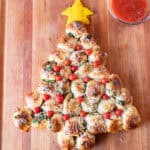Christmas Tree Appetizer on wooden cutting board next to bowl of marinara sauce.