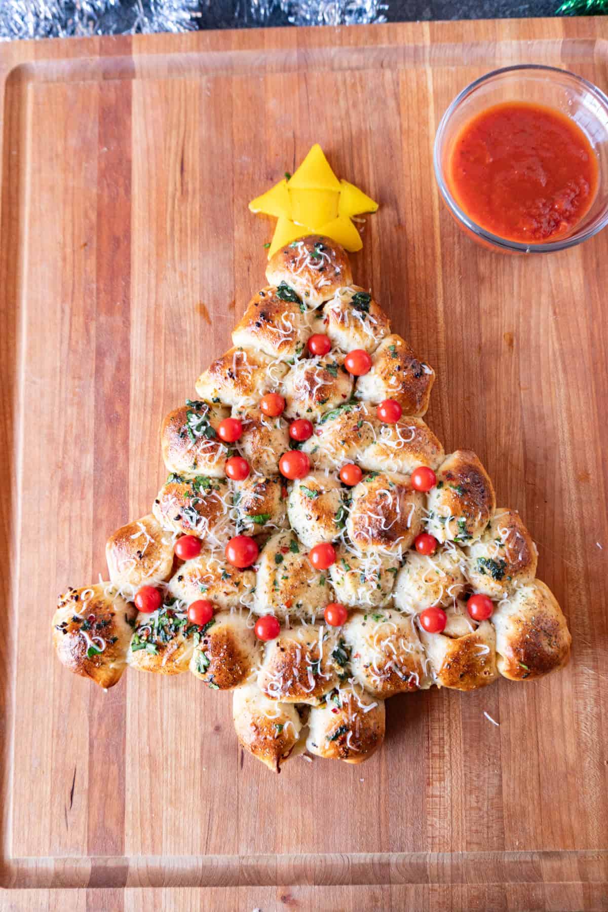 Christmas Tree Appetizer on wooden cutting board next to bowl of marinara sauce.