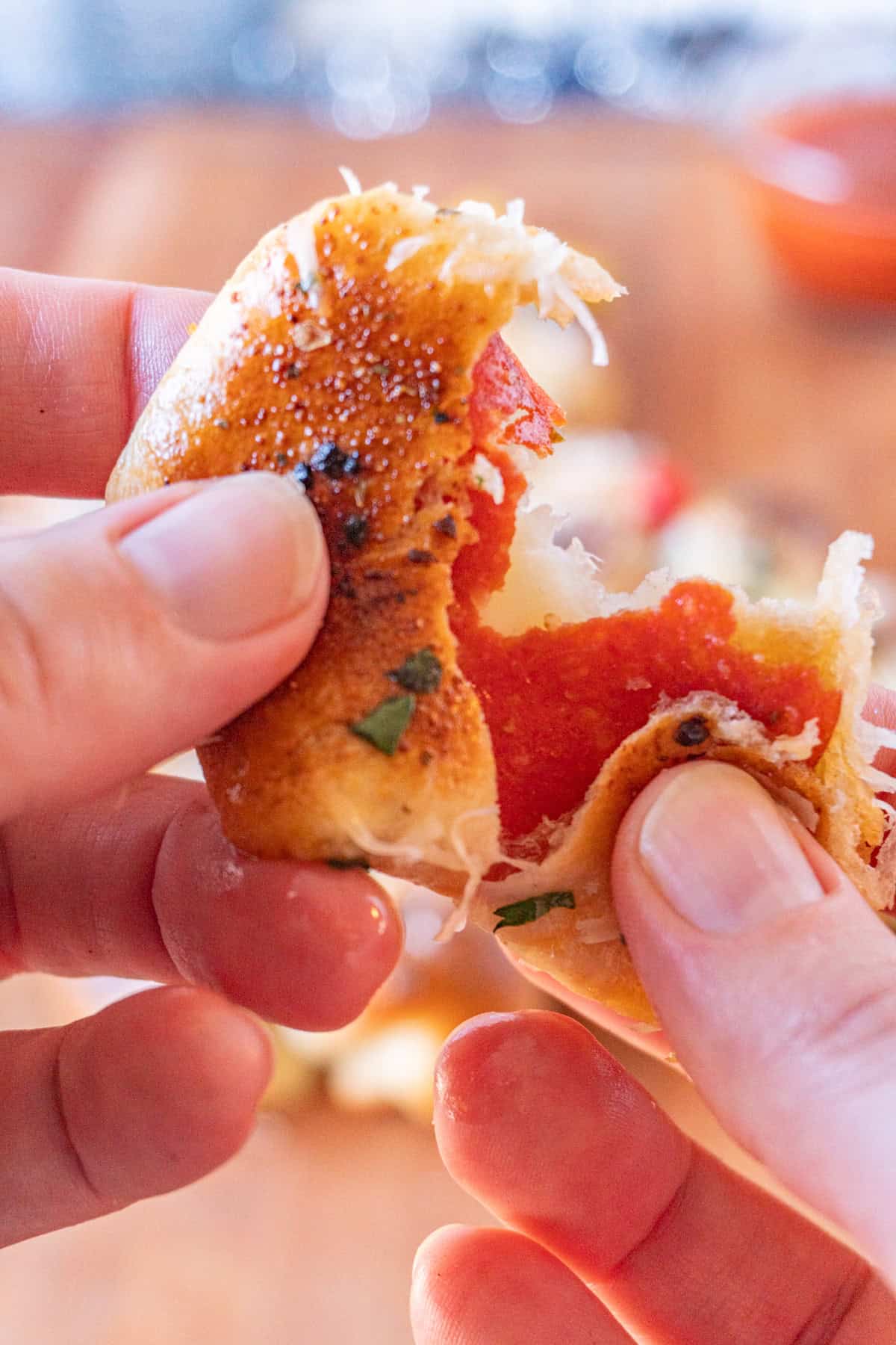 pulling apart a baked dough roll showing the pepperoni and cheese inside.