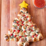 Christmas Tree Appetizer on wooden cutting board next to bowl of marinara sauce.