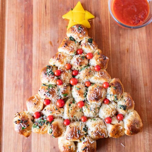 Christmas Tree Appetizer on wooden cutting board next to bowl of marinara sauce.