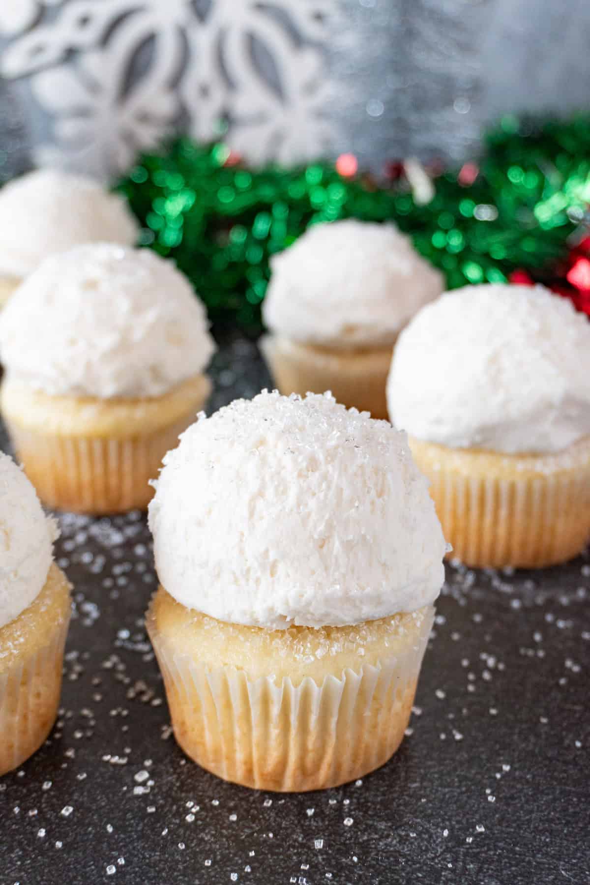 snowball cupcake with sparkly sanding sugar on top, with more cupcakes in background.