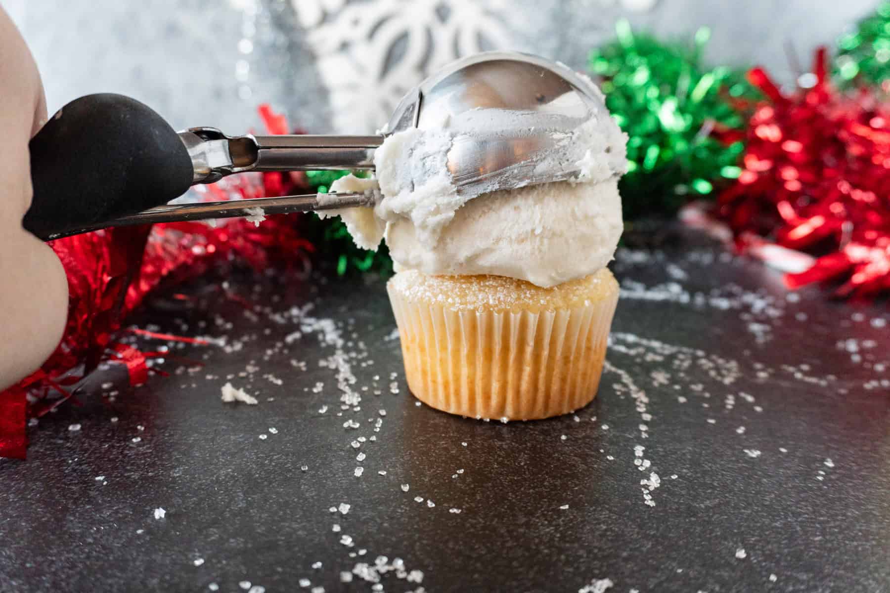 adding a scoop of frosting to the top of a cupcake.