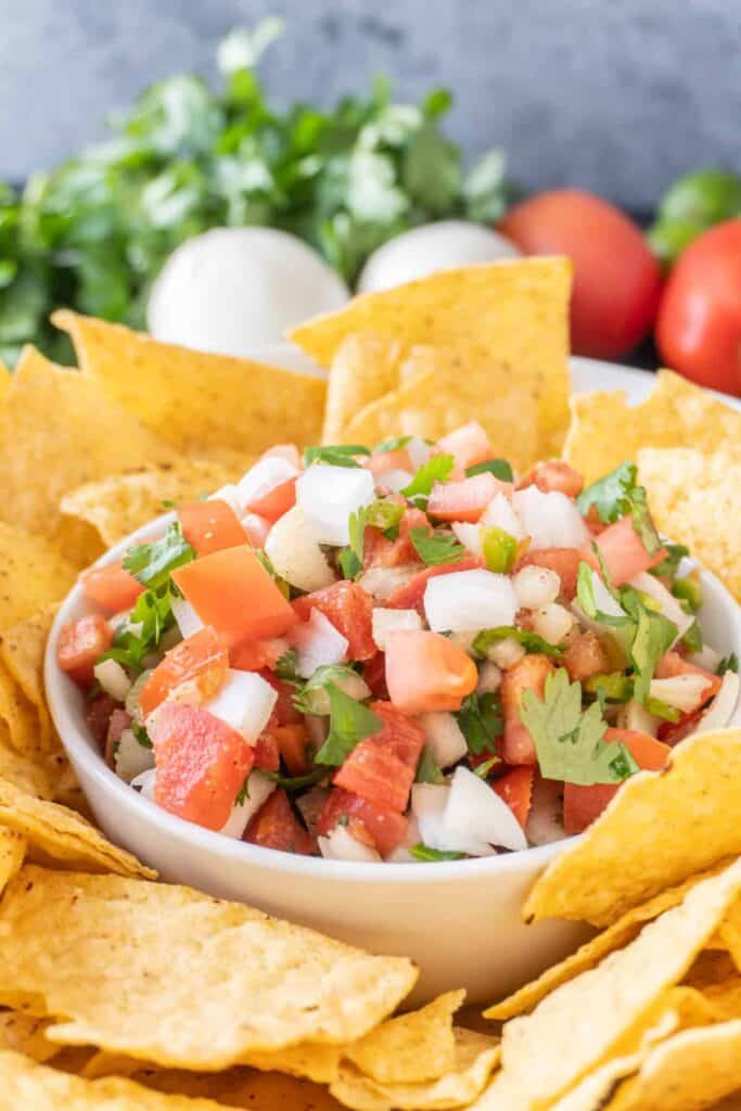 pico de gall in a bowl surrounded by tortilla chips