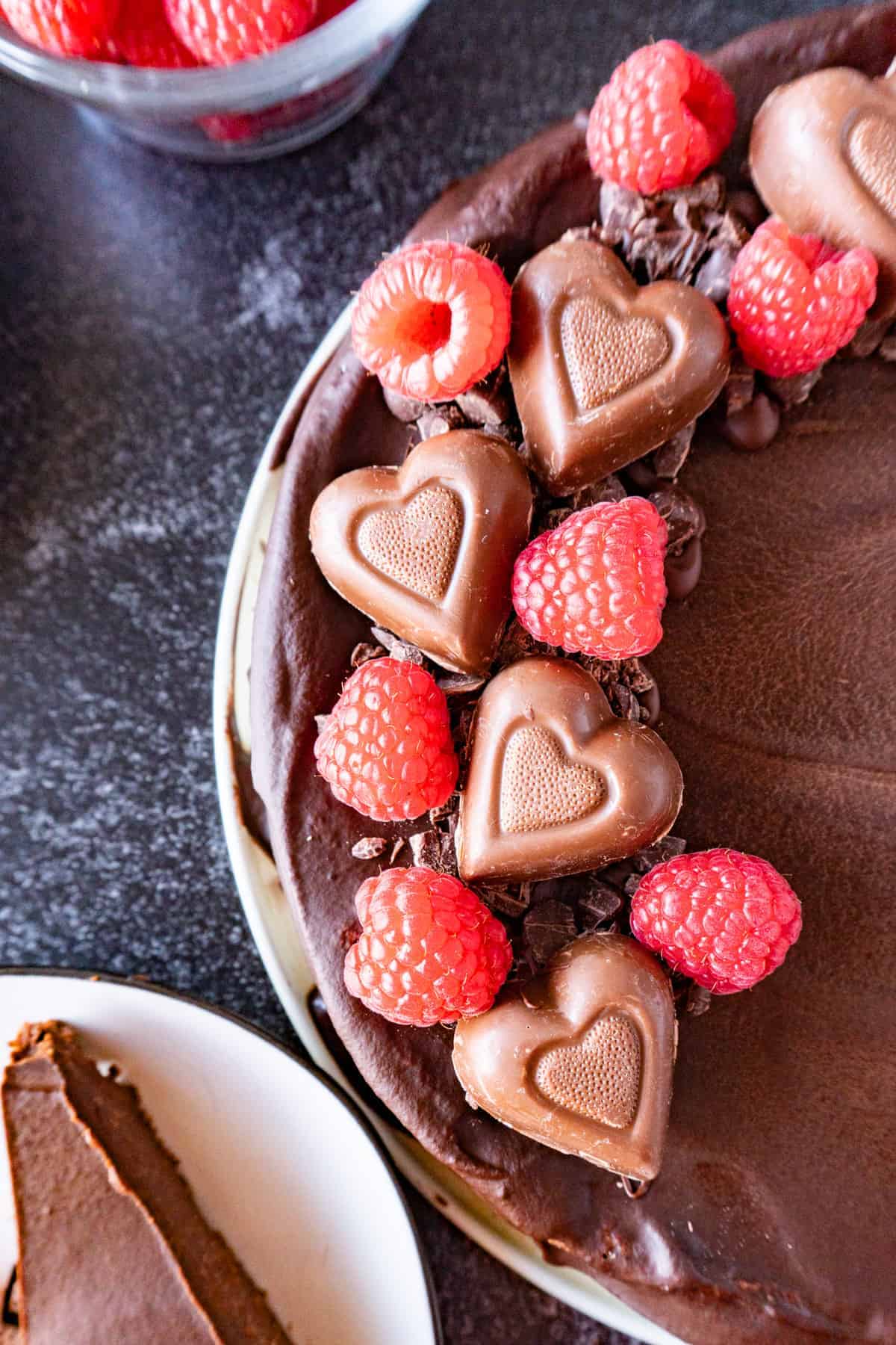 close up of decorated truffle cake (with chocolate pieces, heart candy and raspberries)