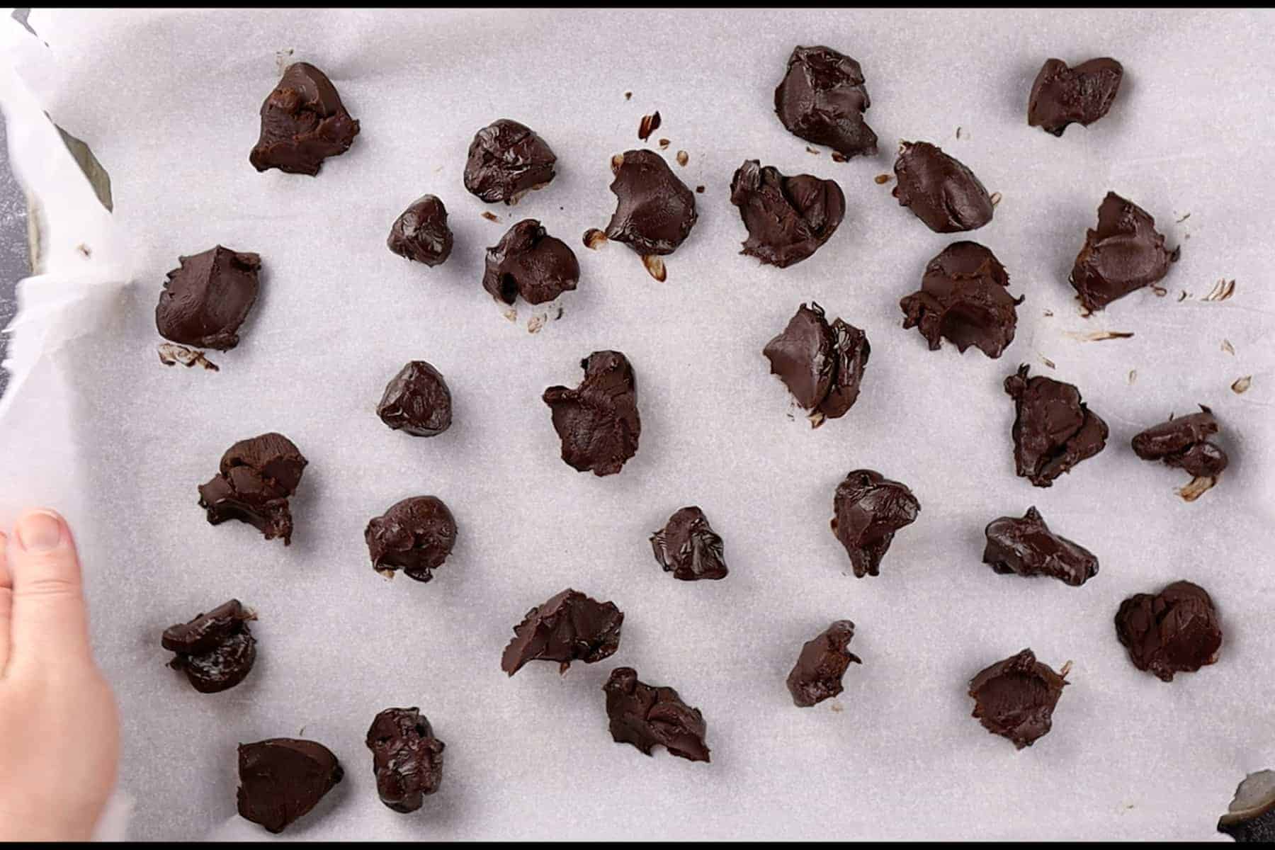 truffle mixture scooped but not rolled yet, on parchment lined baking sheet.
