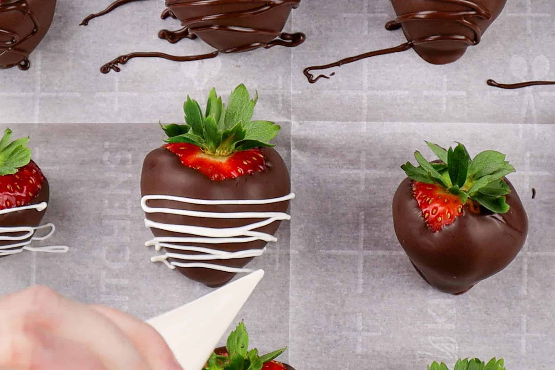 drizzling white chocolate onto chocolate dipped strawberry.