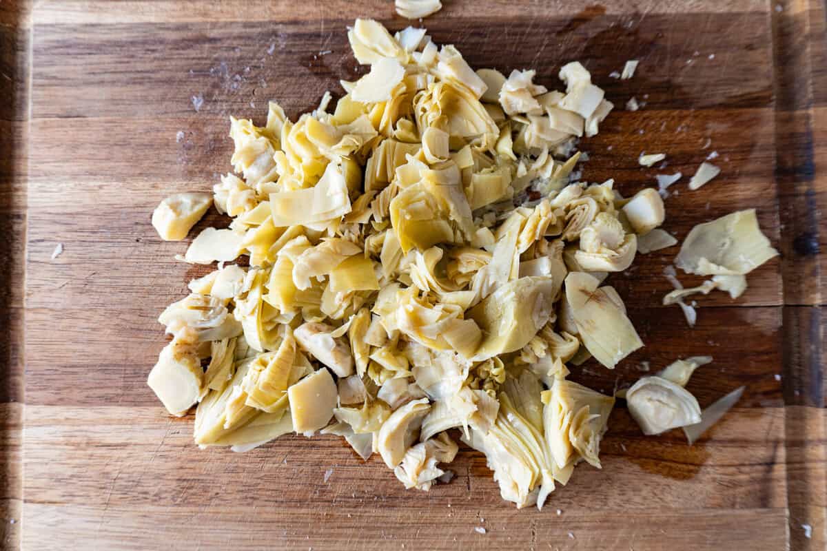 Chopped artichoke hearts on a wooden cutting board.