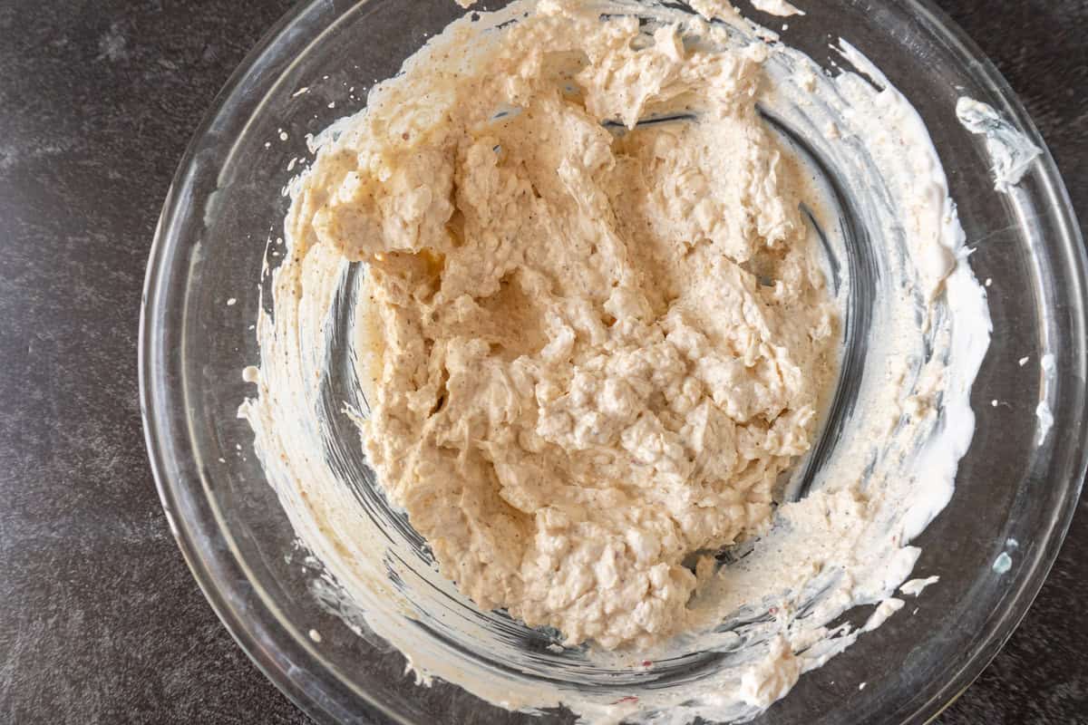 artichoke dip base mixed together in a glass bowl.