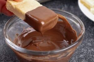 shortbread cookie being dipped in chocolate