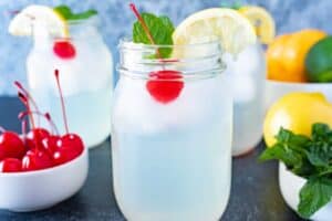 mint julep in a glass with cherrie, lemon wedge, and mint leaf