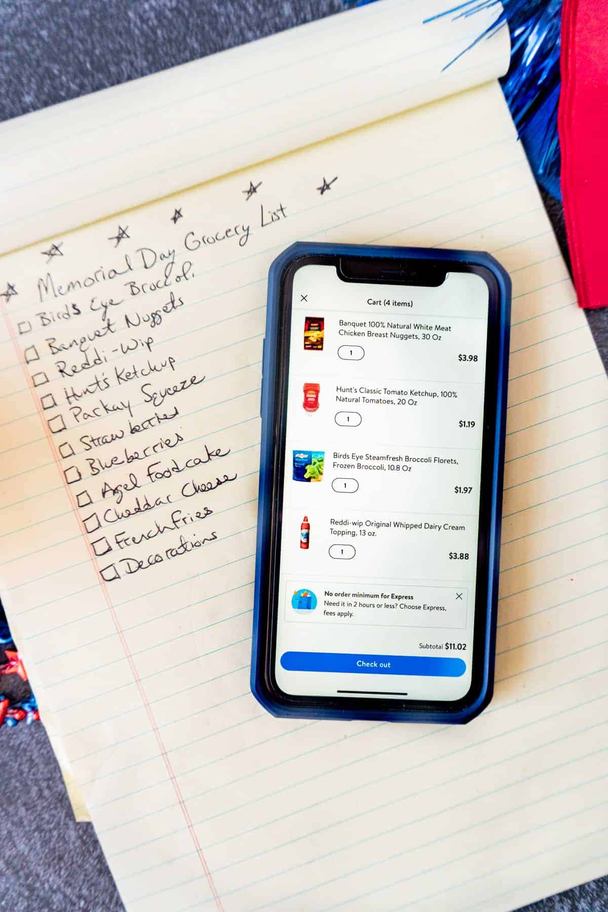 notepad with grocery list and iphone with walmart grocery pickup app open