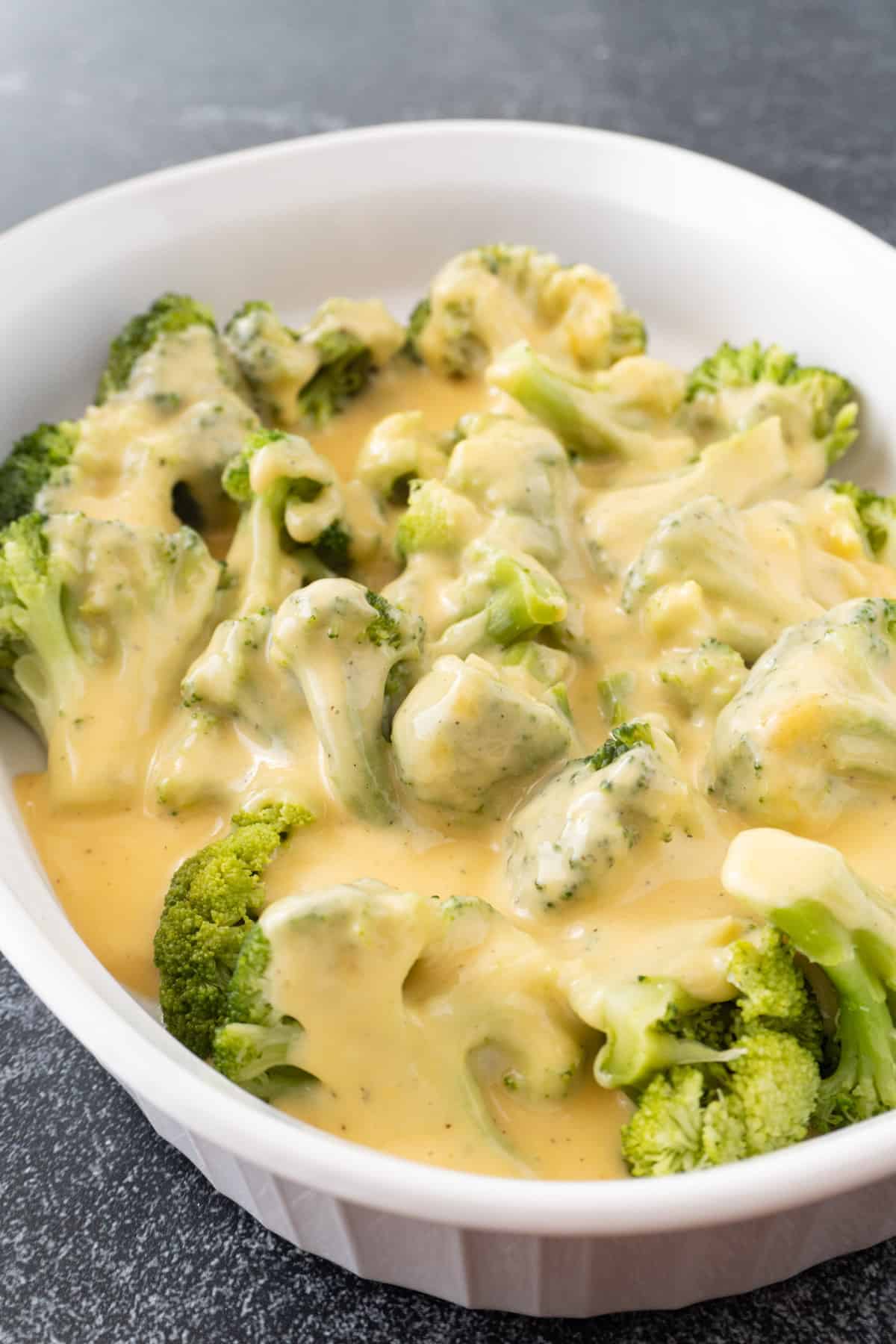 broccoli covered in cheese sauce in a white dish