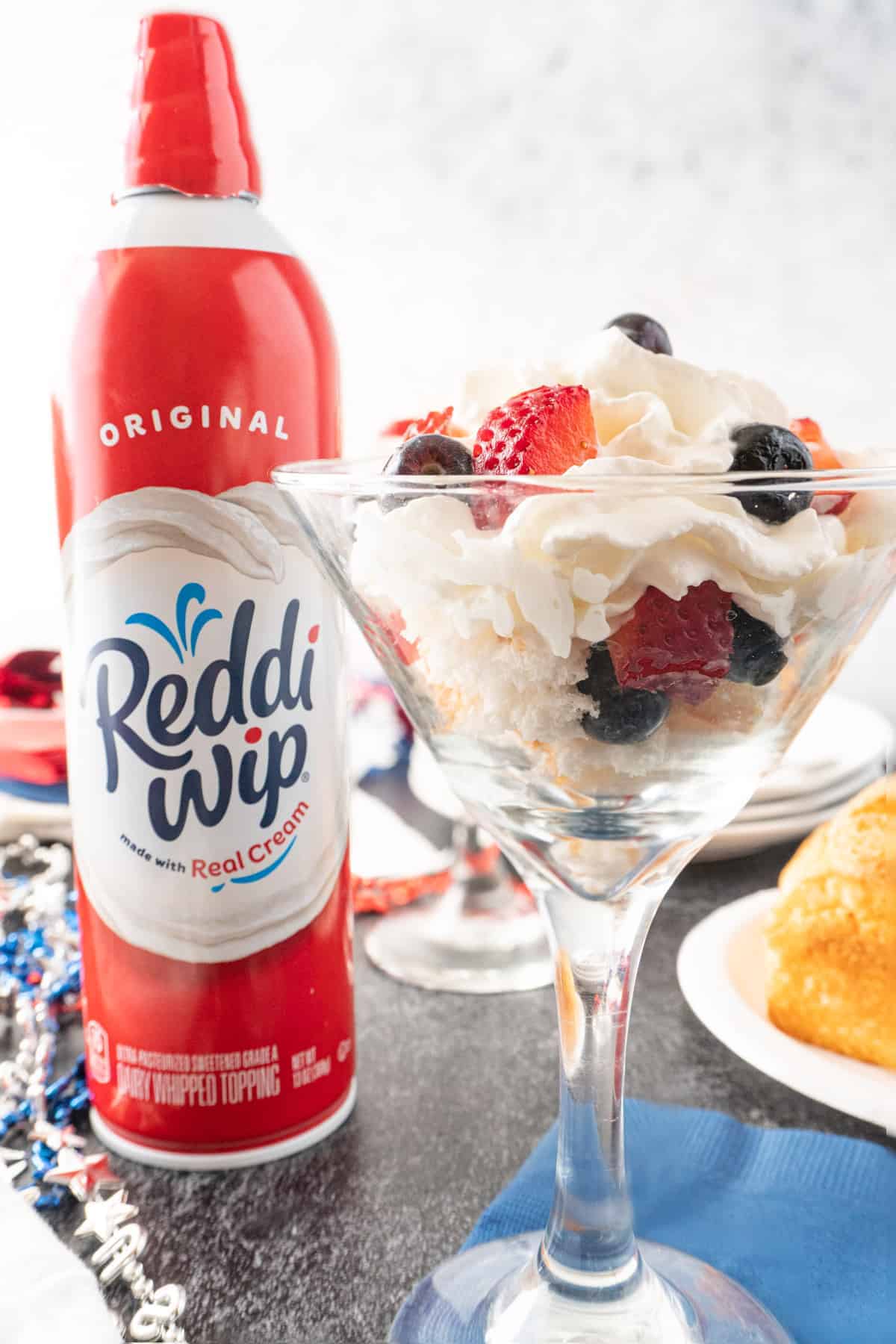 angel food cake, whipped cream, and berries in a glass with Reddi-Whip Can next to it