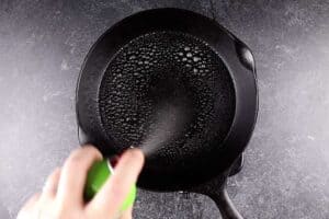 spraying frying pan with non-stick cooking spray