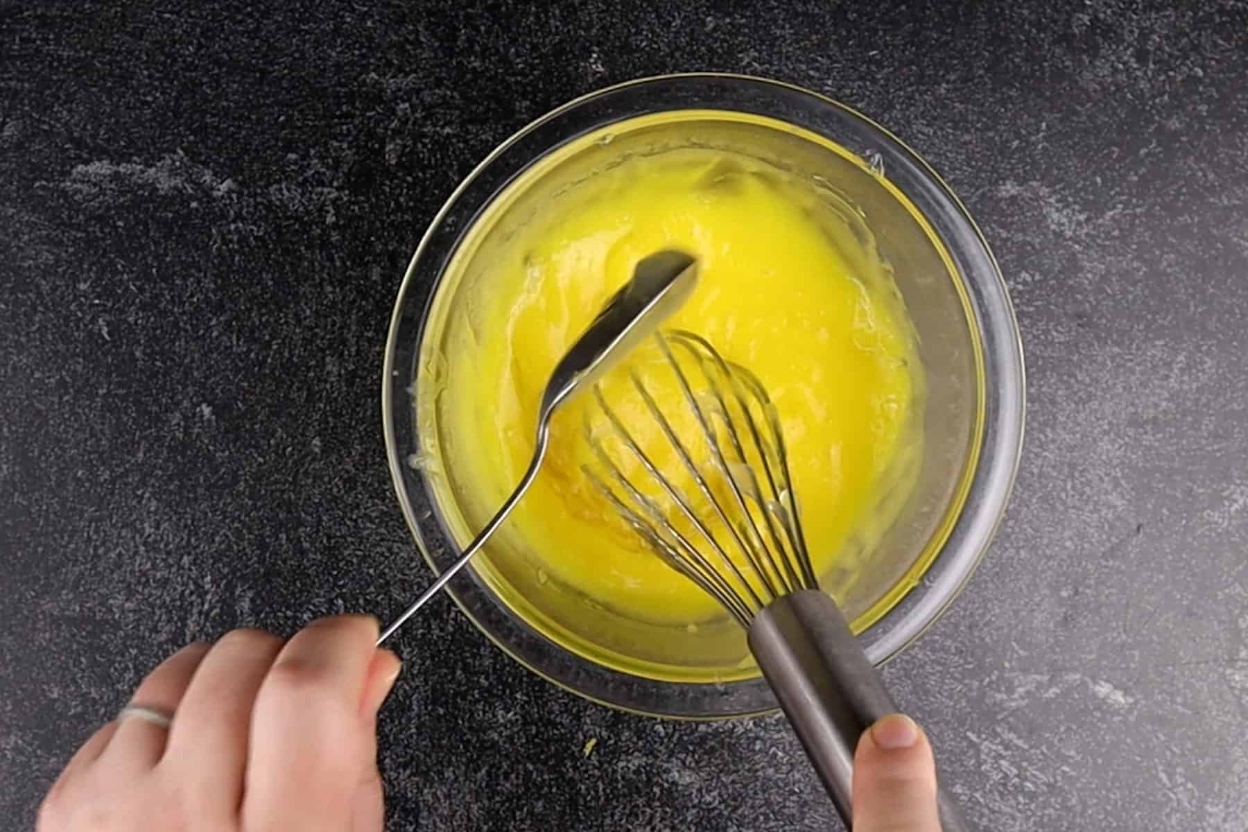 tempering the egg yolks- a spoonful of lemon filling whisked into yolks