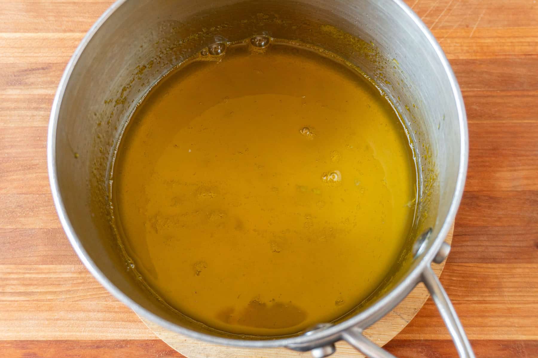 orange juice and sugar boiled together in metal sauce pan.