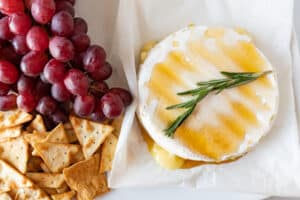brie with honey and rosemary next to crackers and grapes