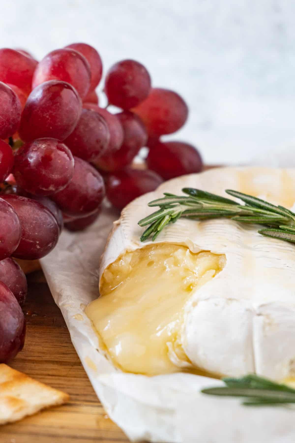 brie with melted cheese pouring out with grapes in background