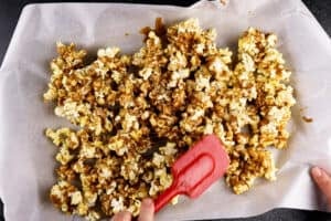 stirring popcorn on baking sheet after it has baked for 15 minutes