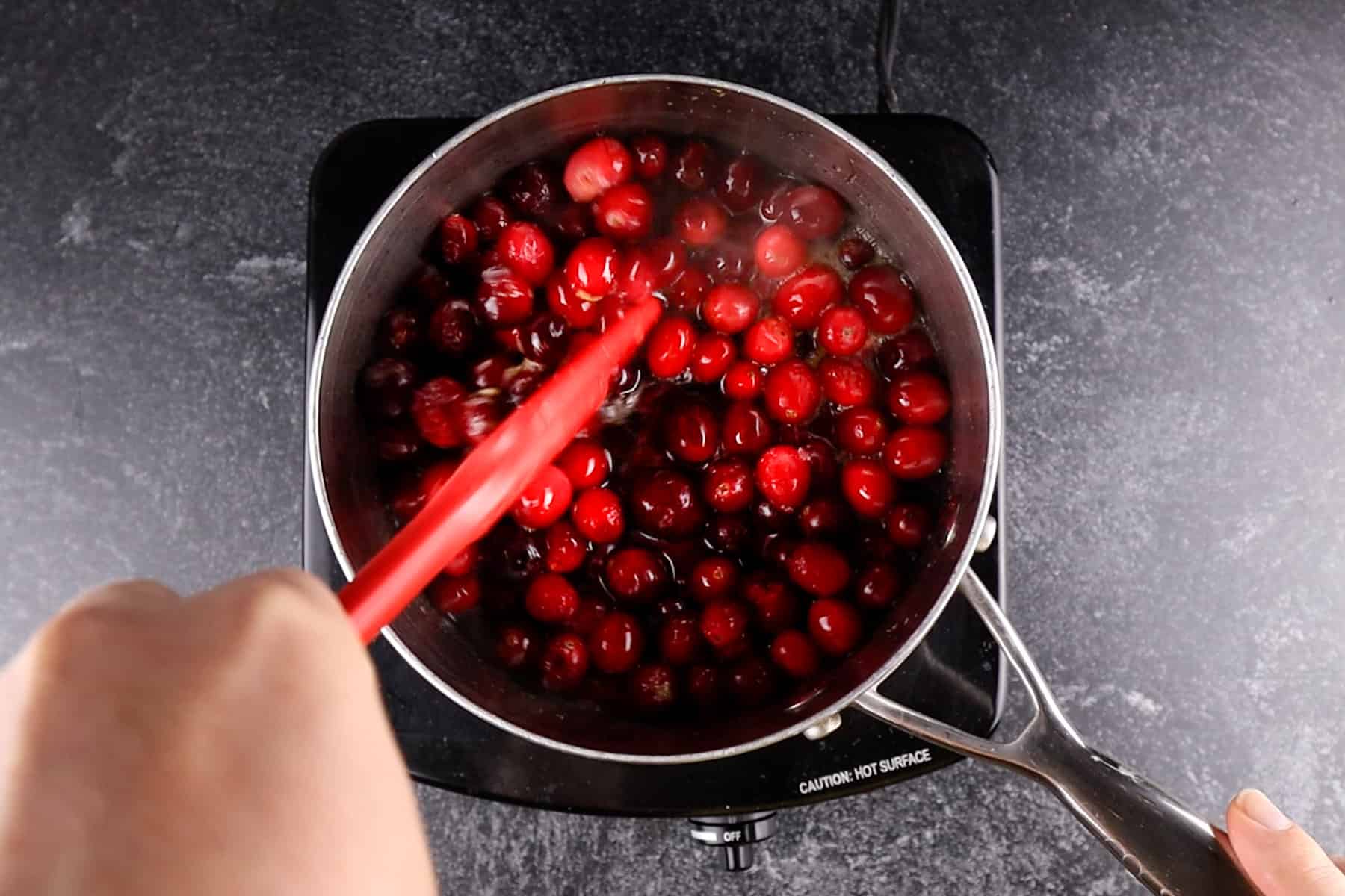 stirring cranberries in saucepan