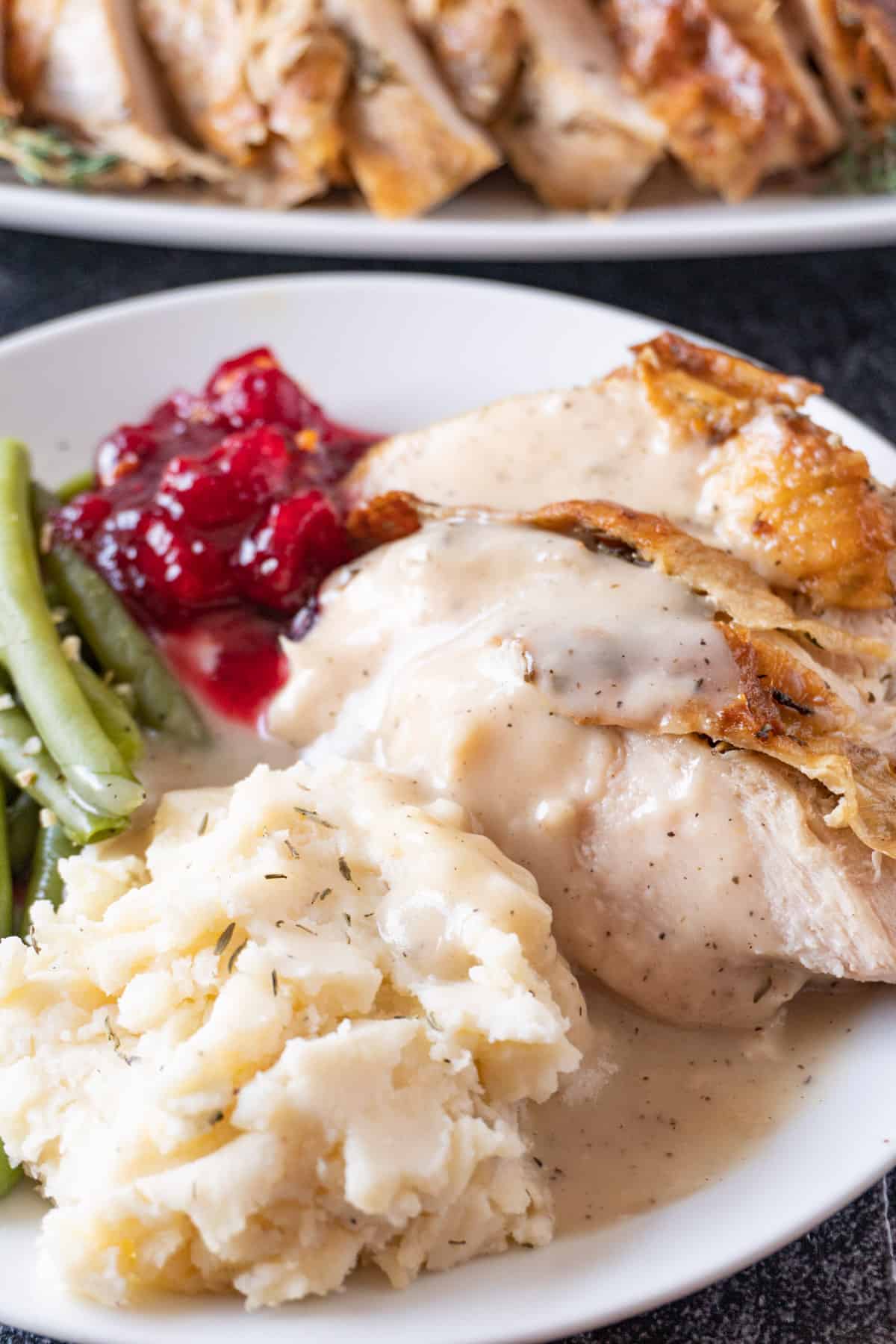 plate with turkey, mashed potatoes, green beans, cranberry sauce and gravy