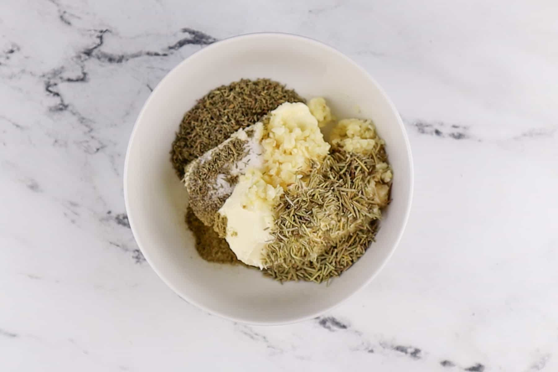 butter and herbs in bowl before mixing