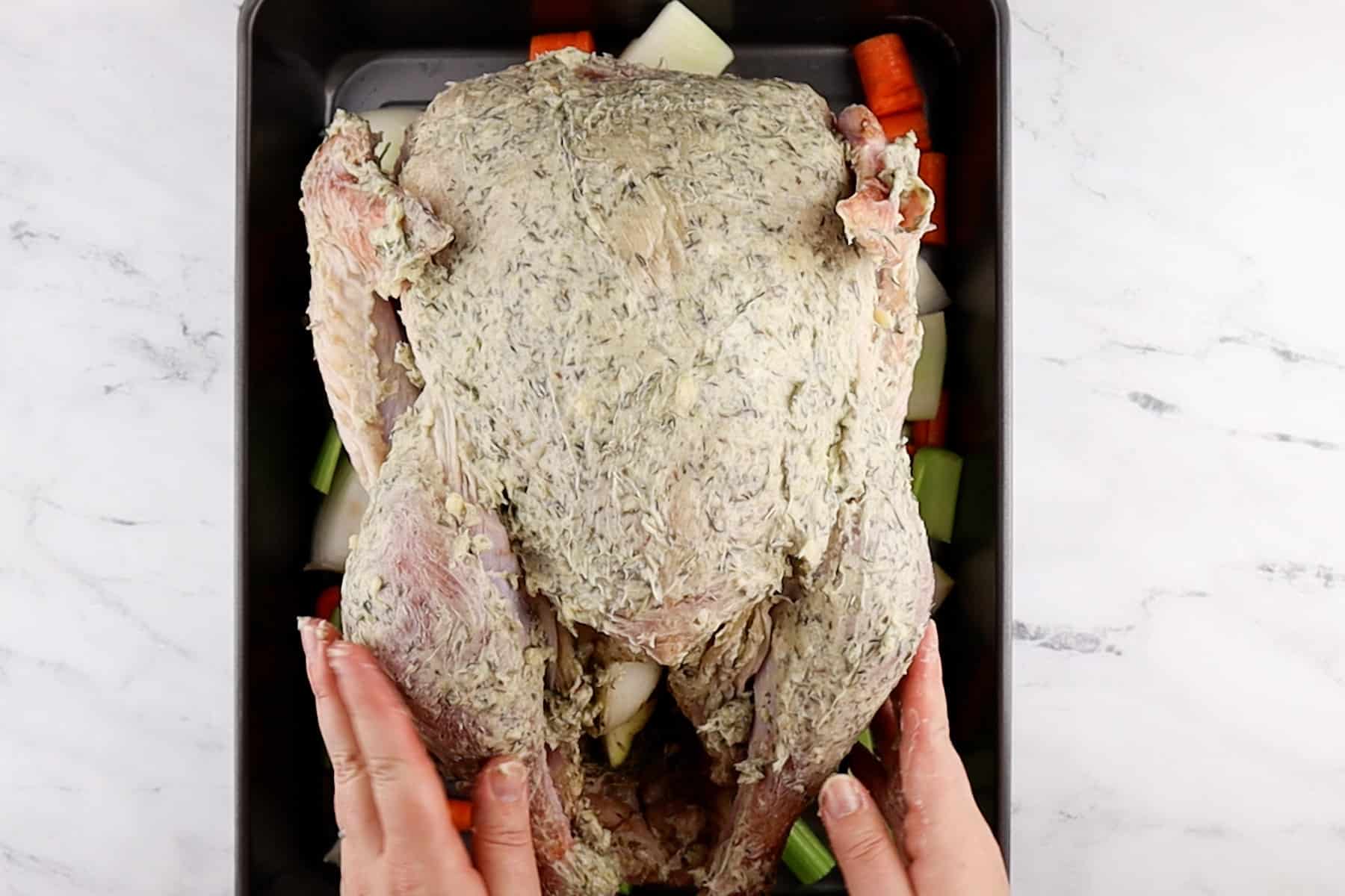 turkey covered in butter on roasting pan before baking