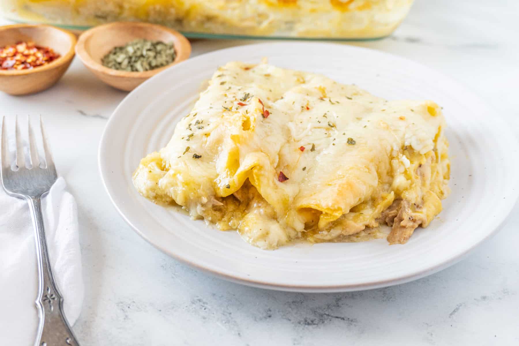 enchilada on plate with fork next to it