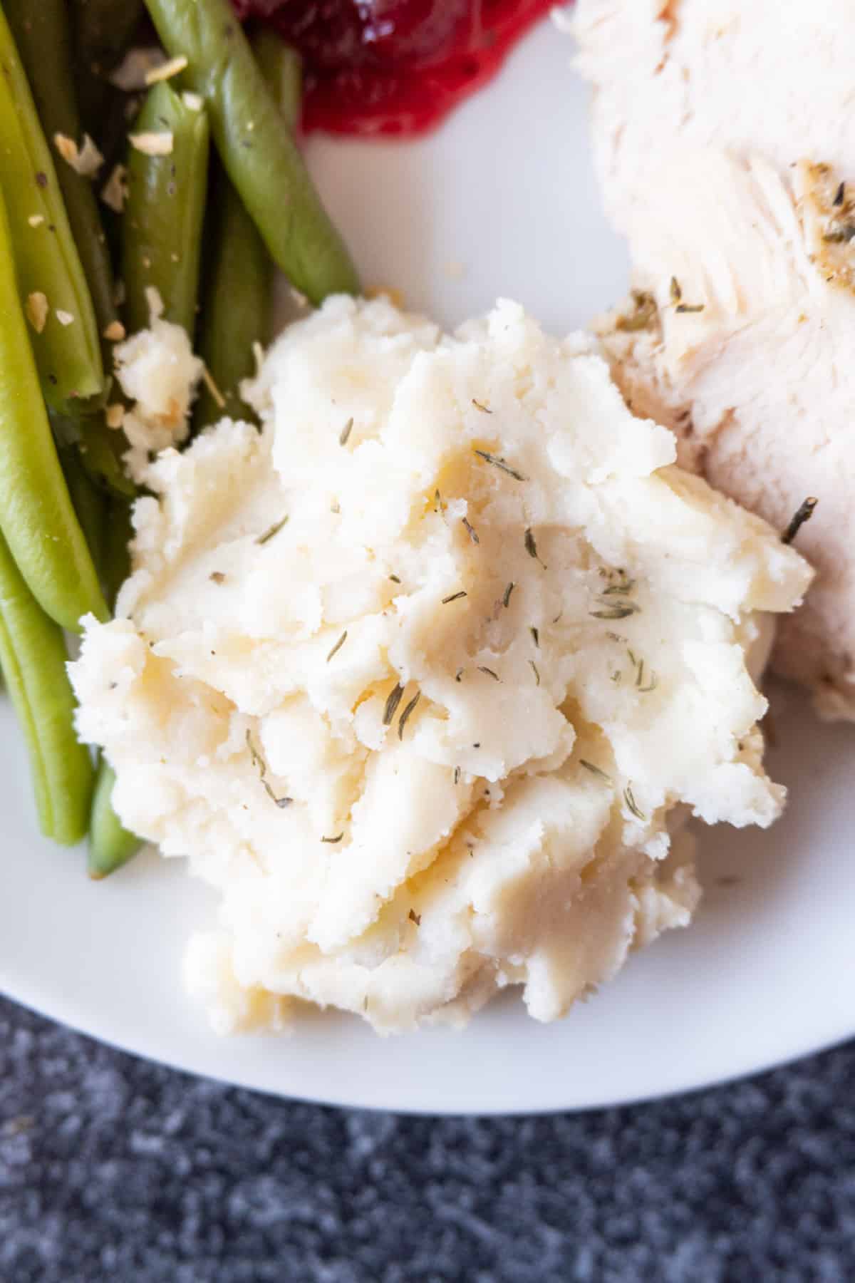 close up of mashed potatoes on plate with green beans