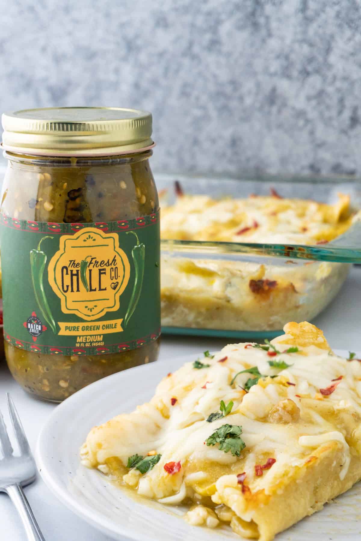 enchilada on plate with green chile in jar