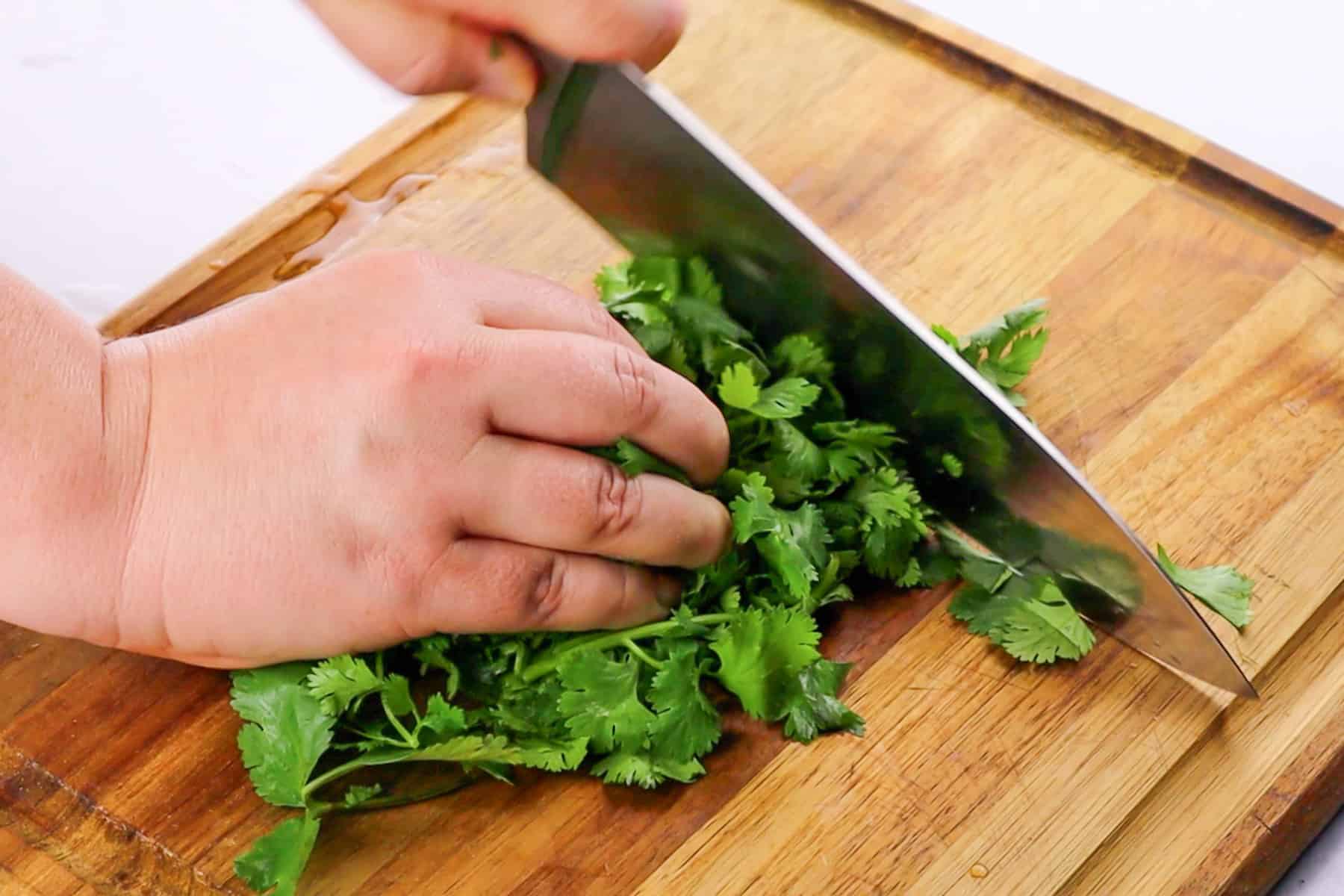 cutting the cilantro on wooden cutting board with chef knife