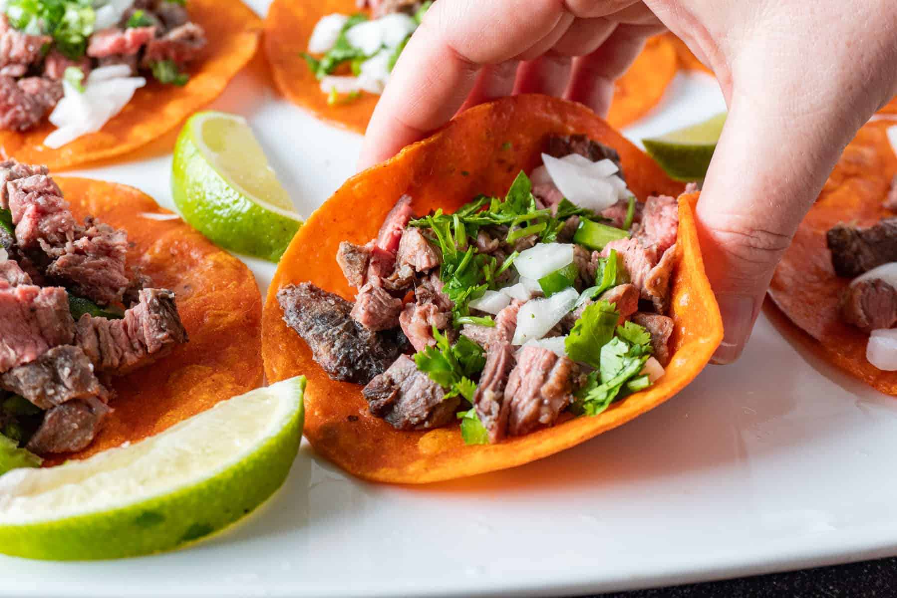 taco with red tortilla, chopped steak, diced onion and fresh cilantro on top