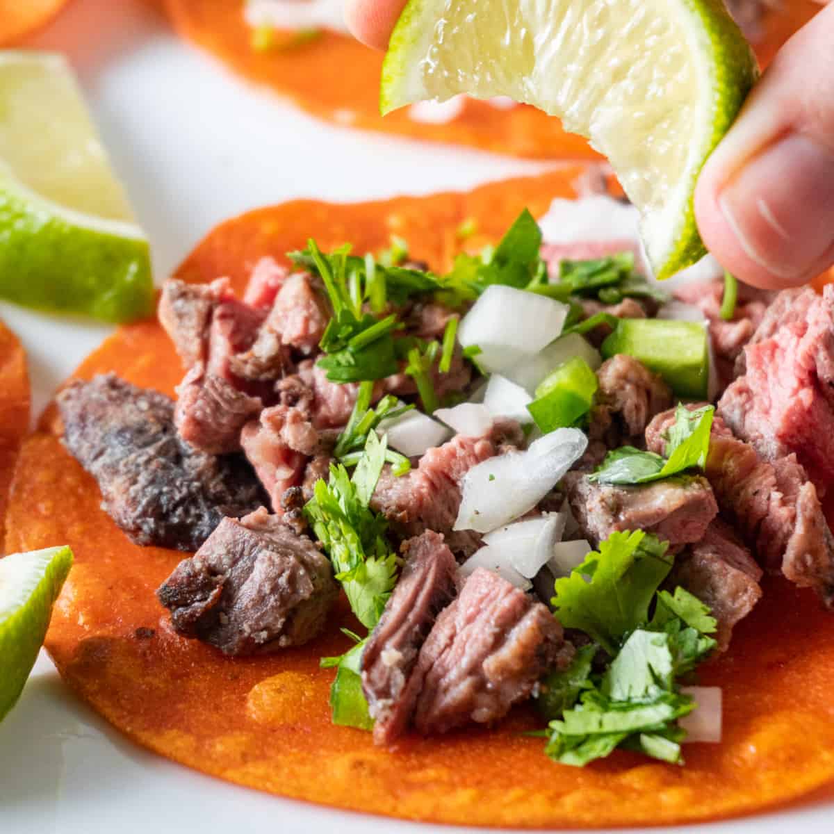 squeezing lime wedge over taco featured image