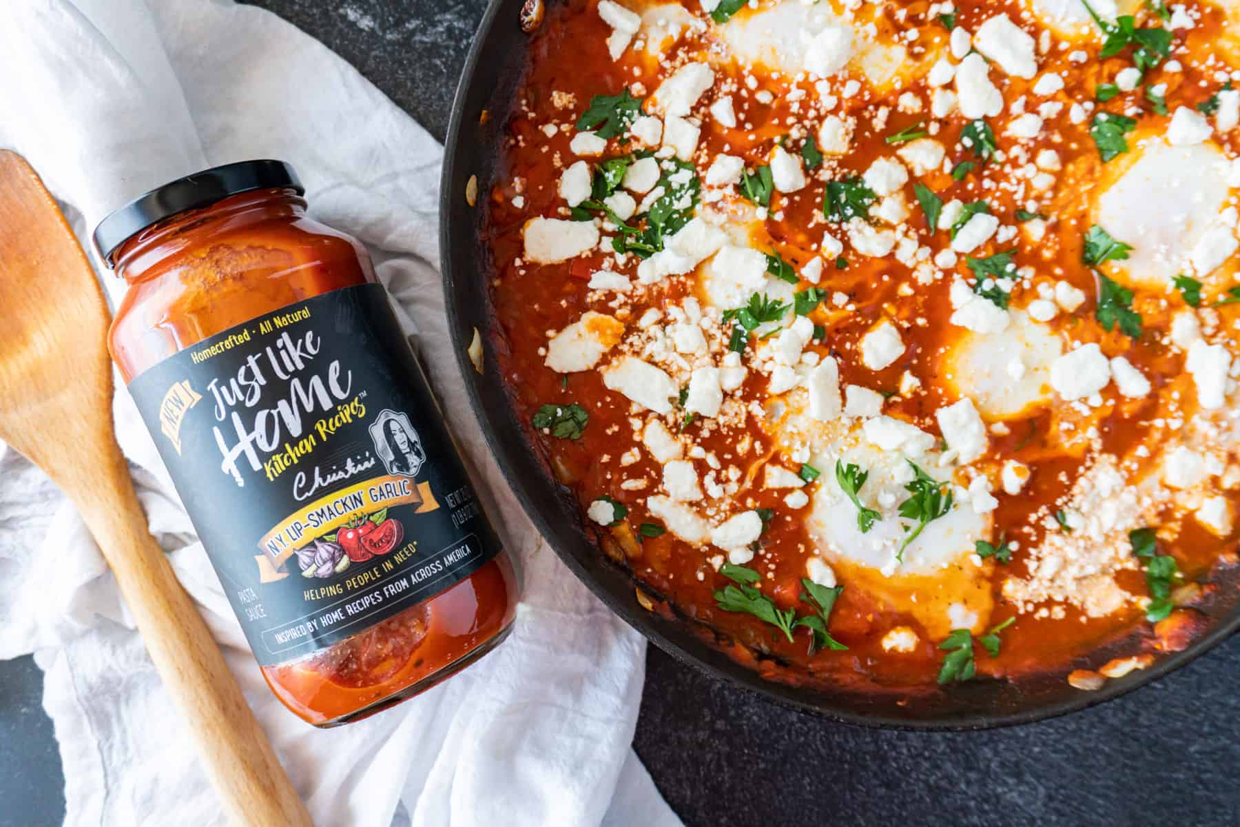 shakshuka in skillet next to jar of pasta and wooden spoon