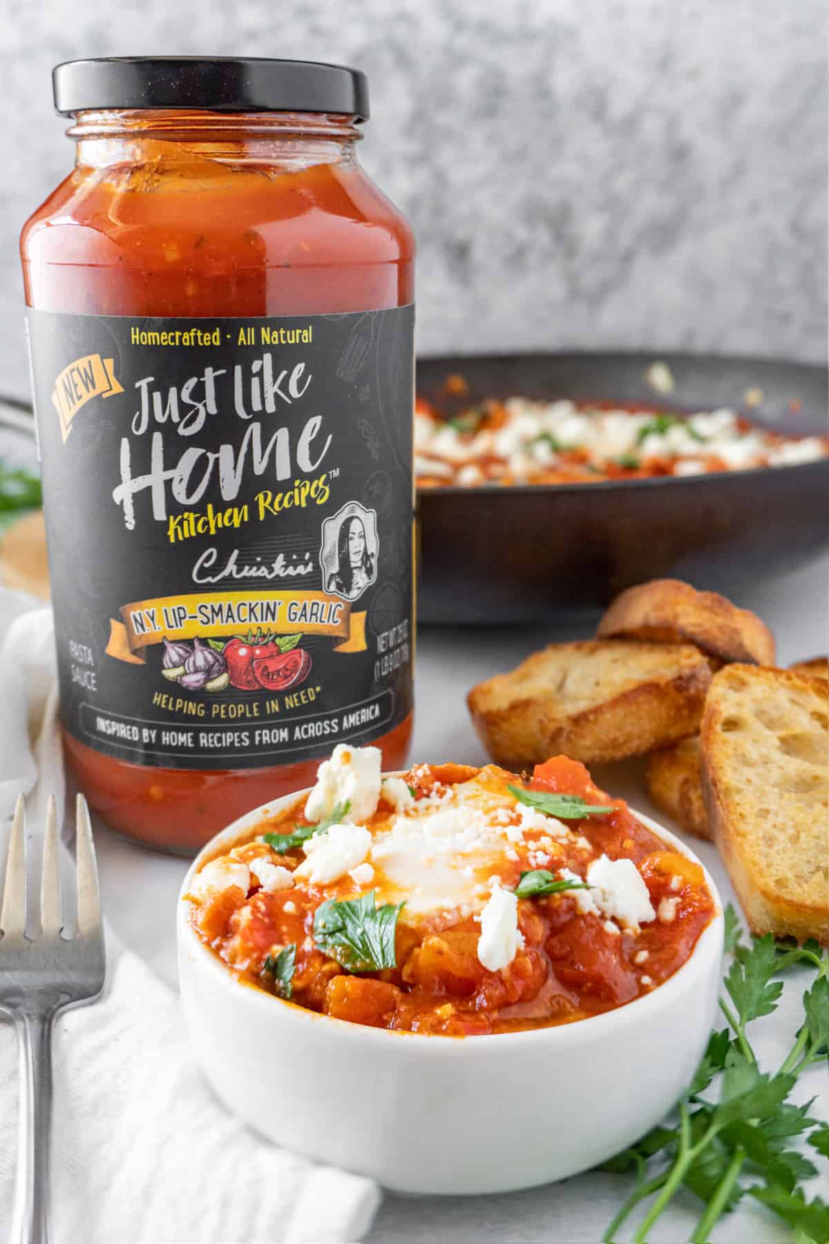 shakshuka with feta and parsley in bowl with jar of pasta