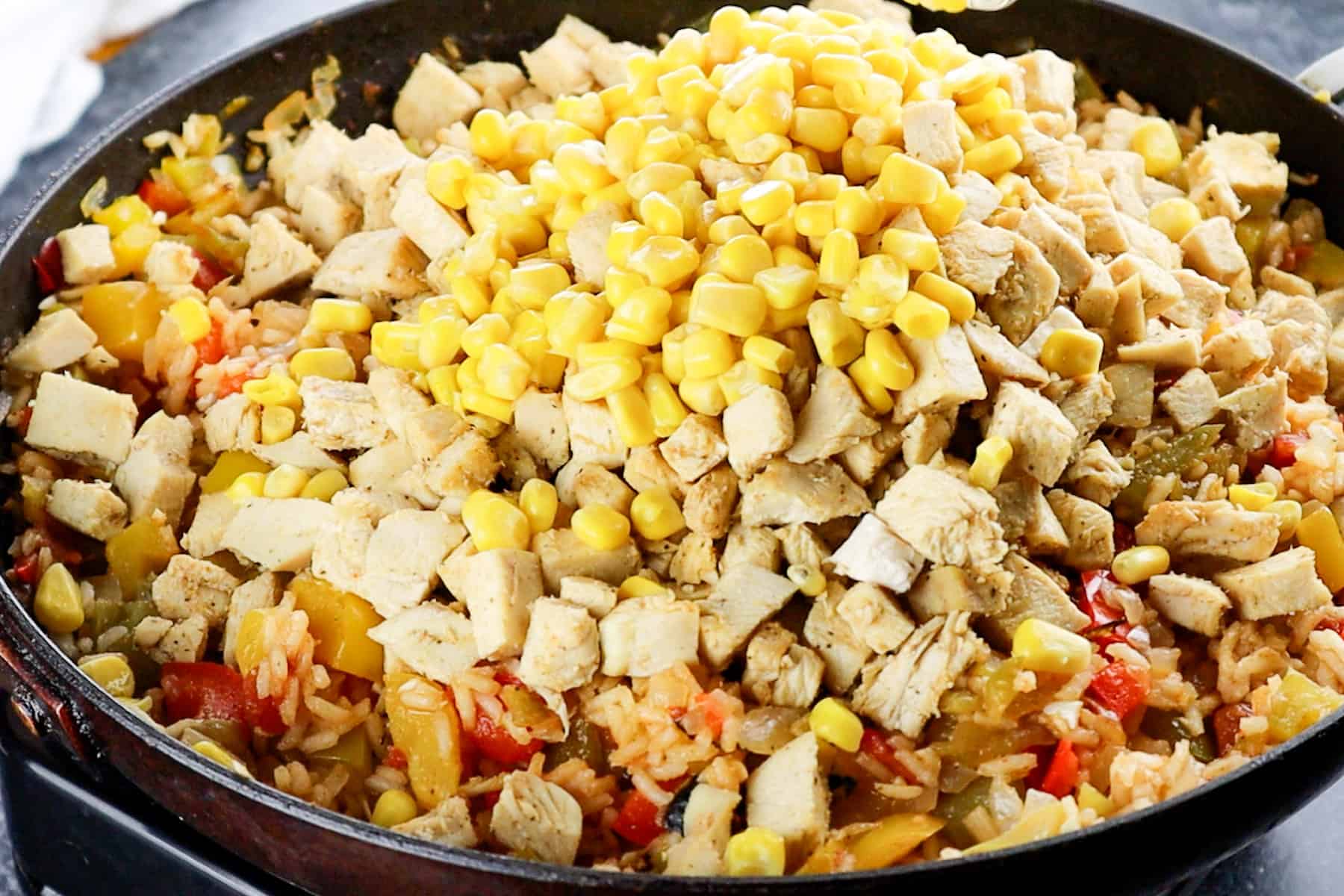 adding corn and chicken to skillet