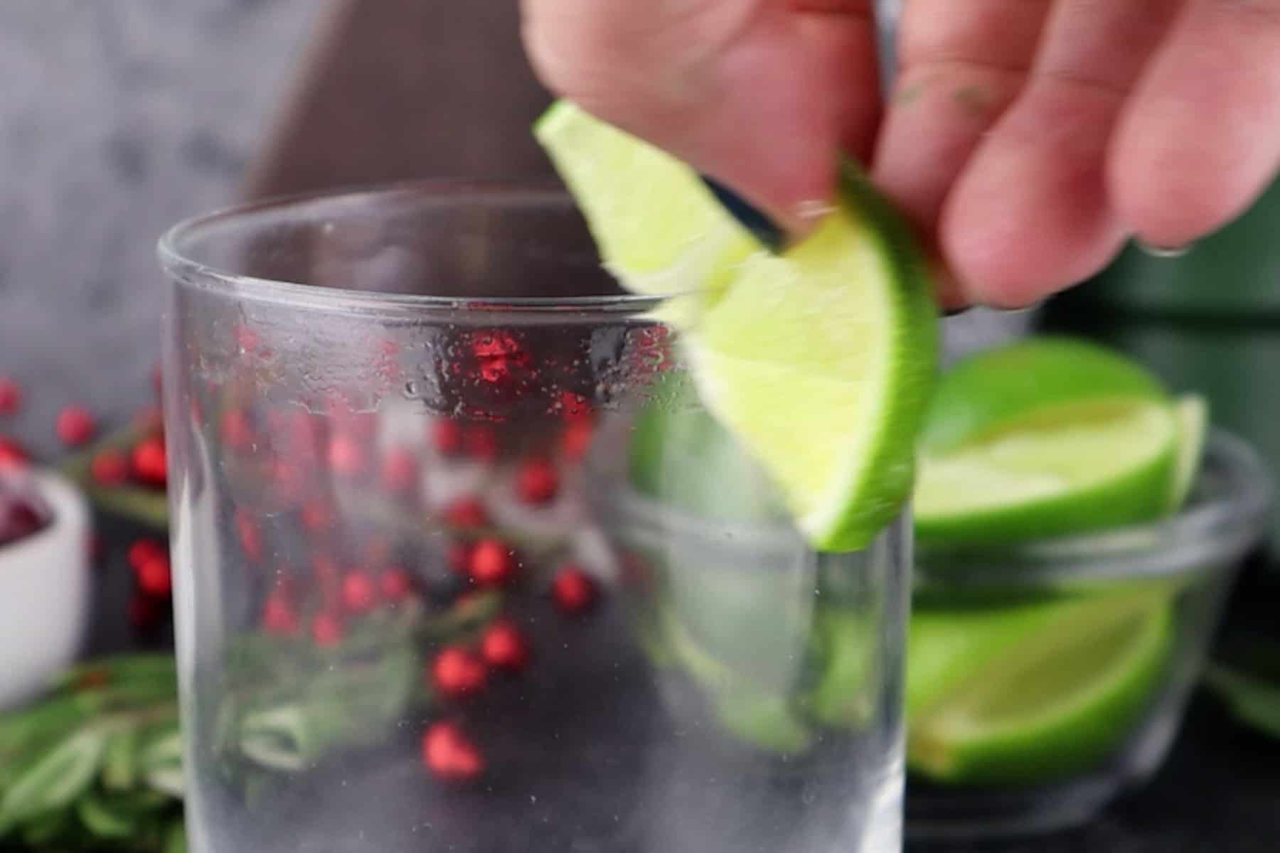 rubbing lime wedge along rim of glass.