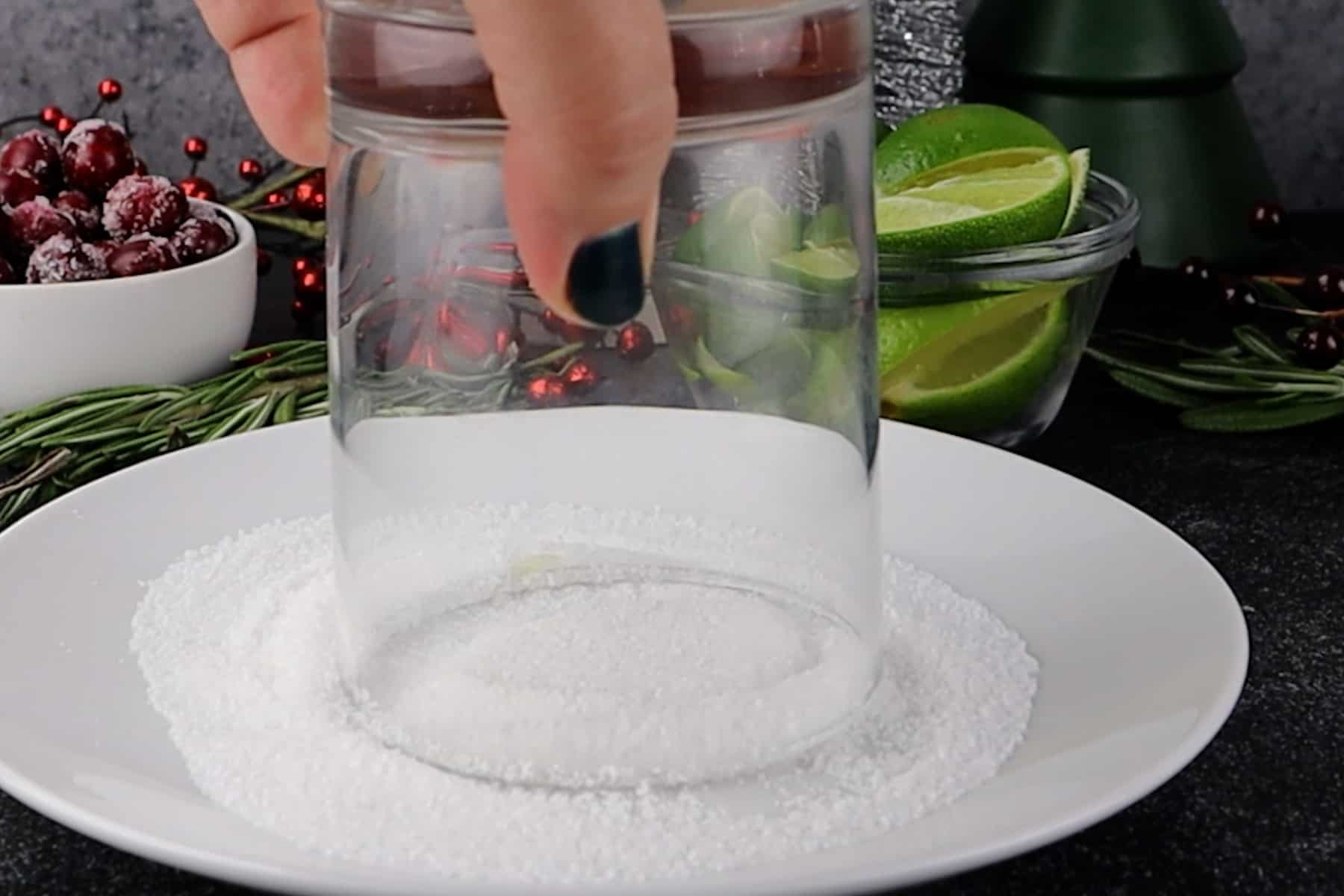 gently pressing rim of glass into sugar and salt on a white plate.