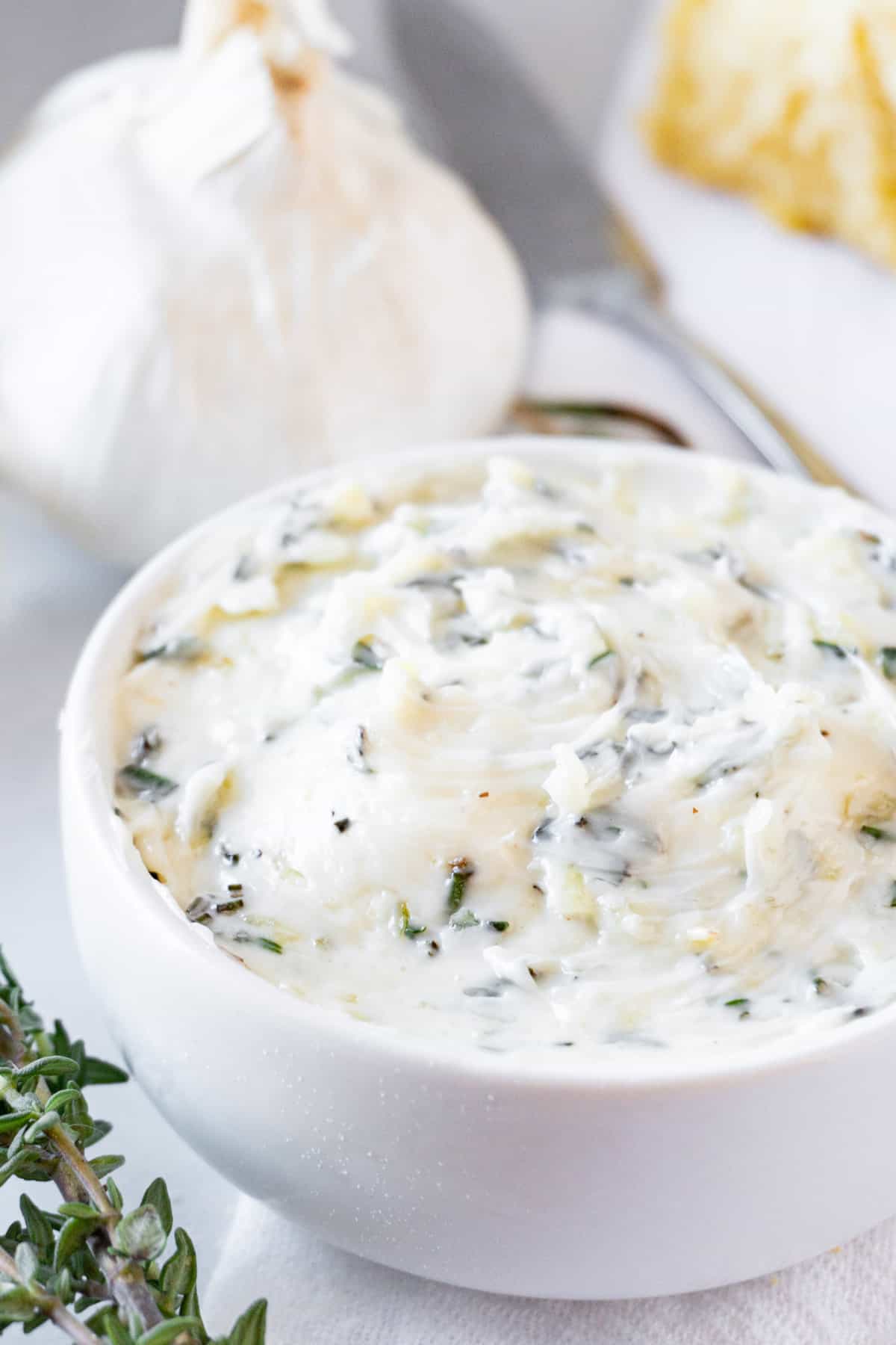 garlic herb butter in bowl with garlic in background