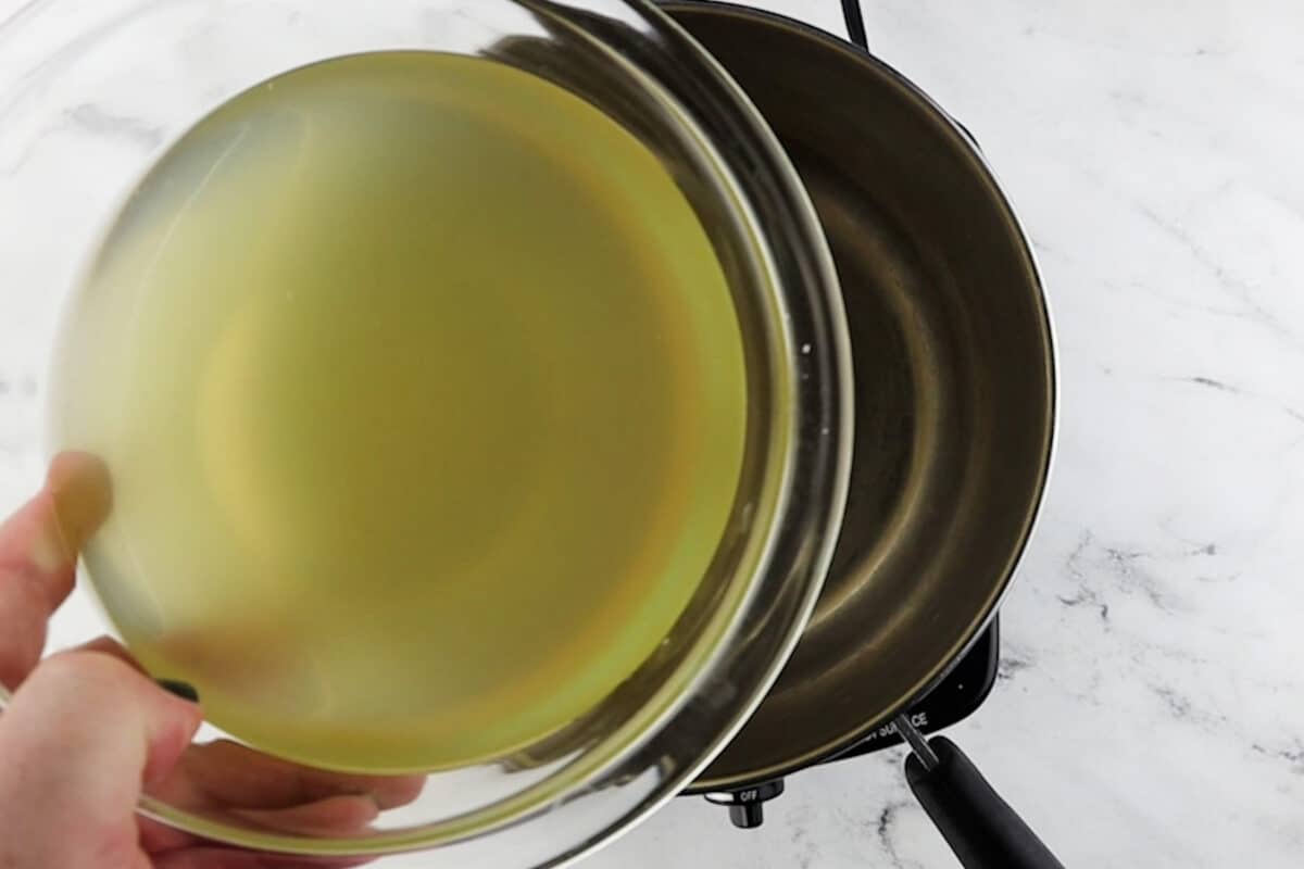 adding broth to saucepan