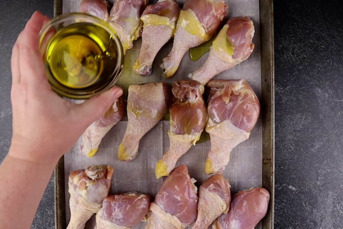 adding olive oil to chicken legs