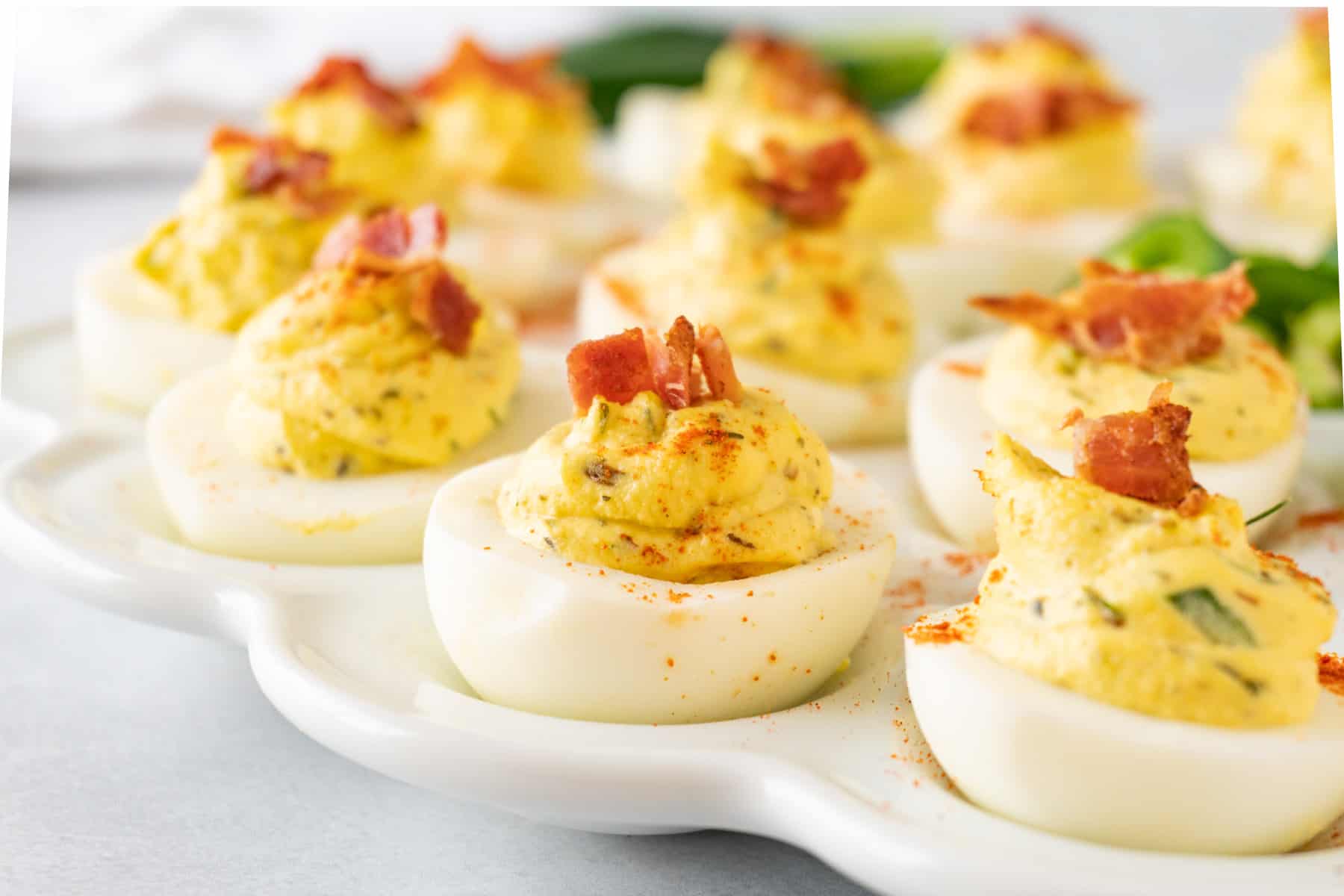 deviled eggs on platter with bacon on top
