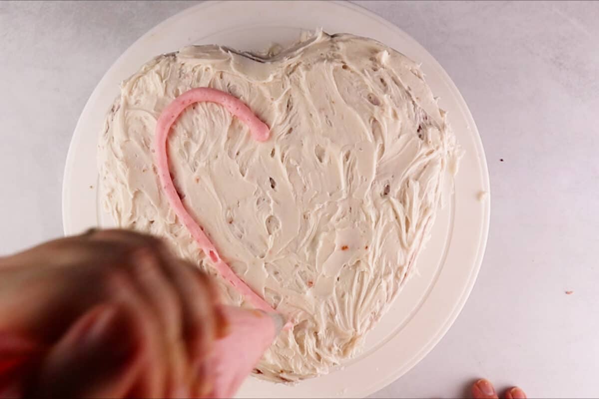 starting to pipe heart on top of cake